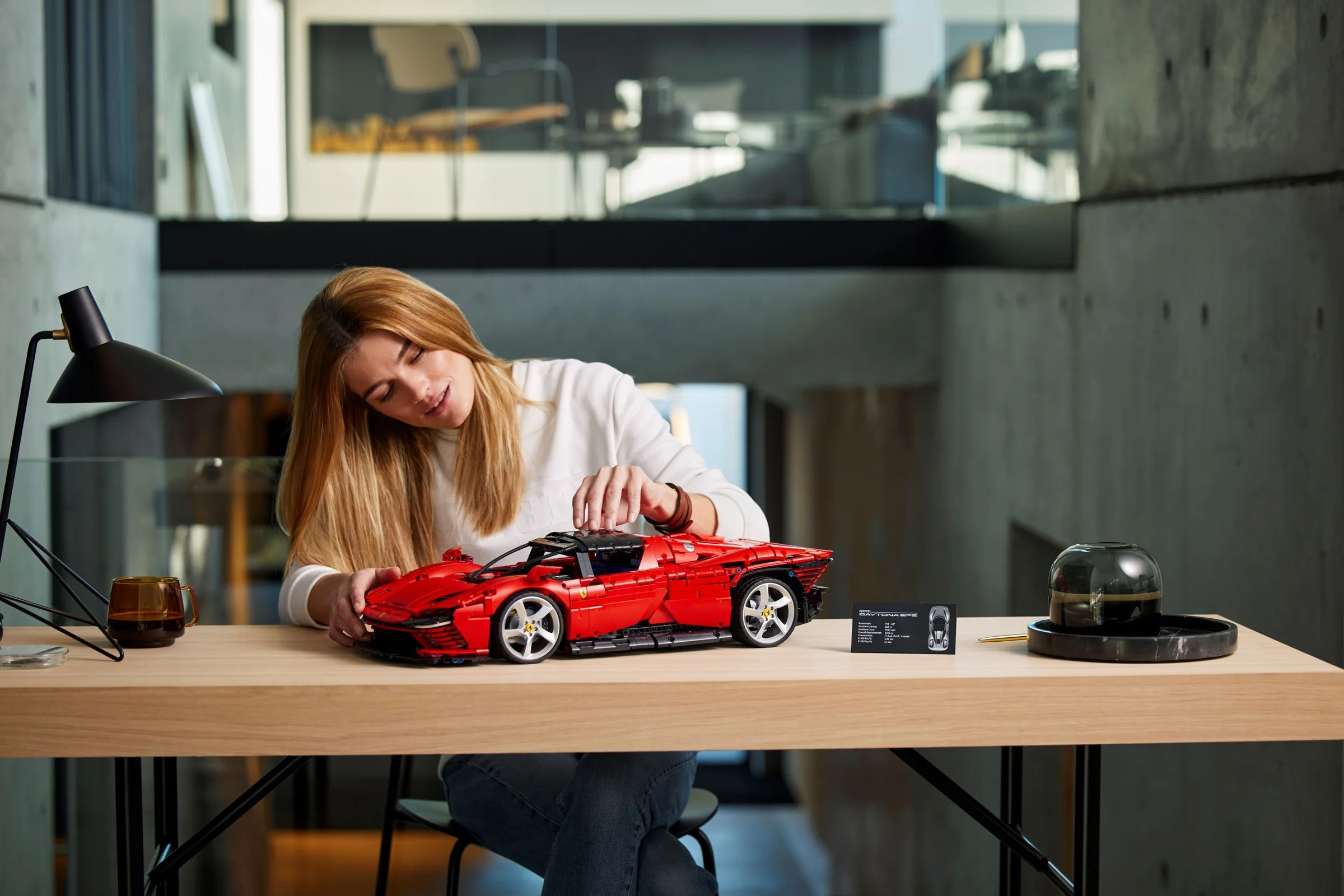 Femeie construind modelul Ferrari Daytona SP3. Modelul roșu și detalii.