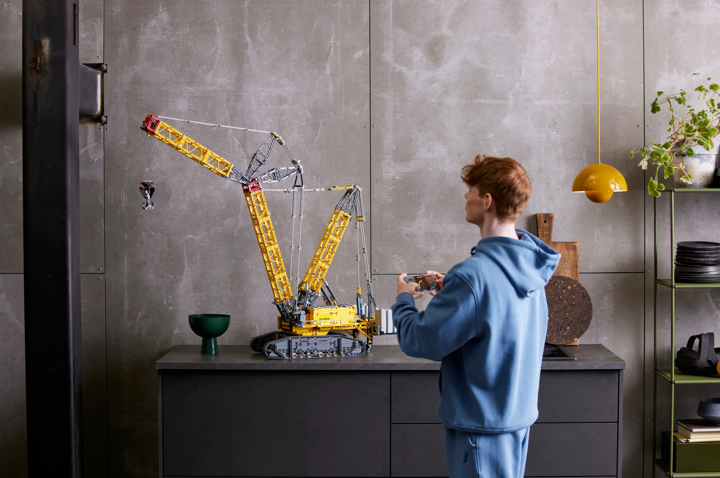Crawler Crane LR 13000 expusă, cu o persoană interacționând cu modelul.