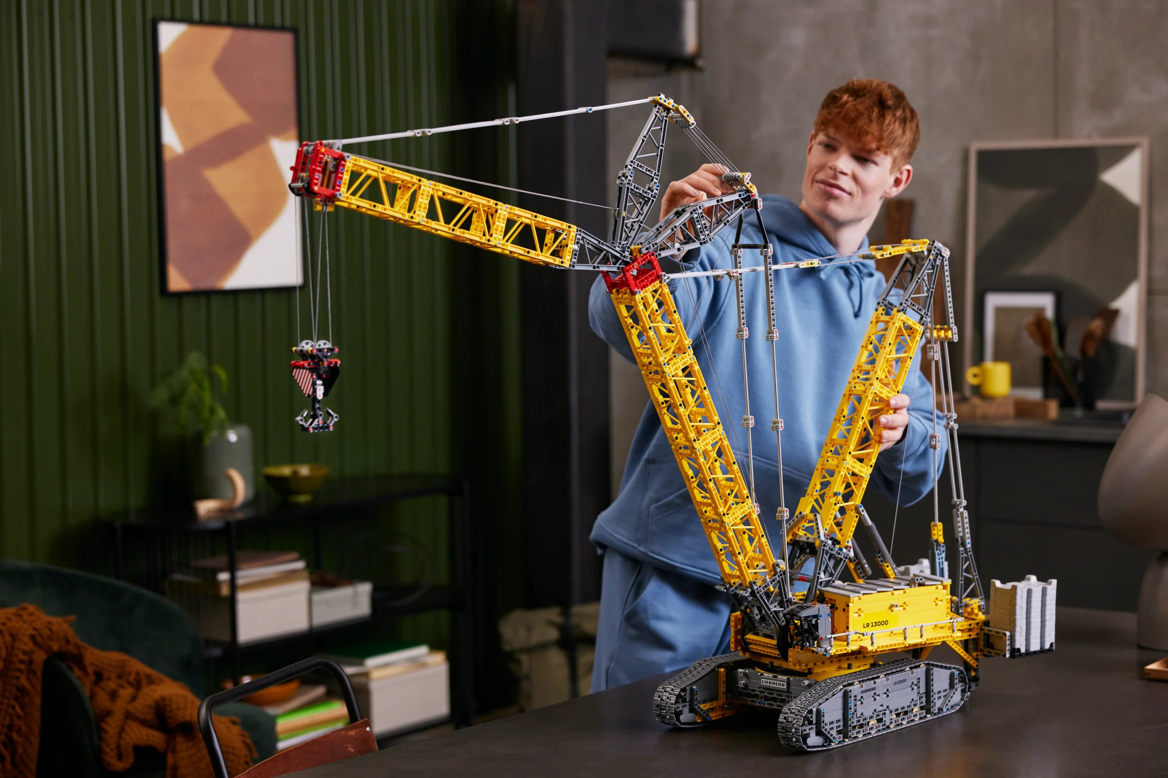 O persoană interacționează cu modelul LEGO Liebherr LR 13000, evidențiind complexitatea și dimensiunea sa.