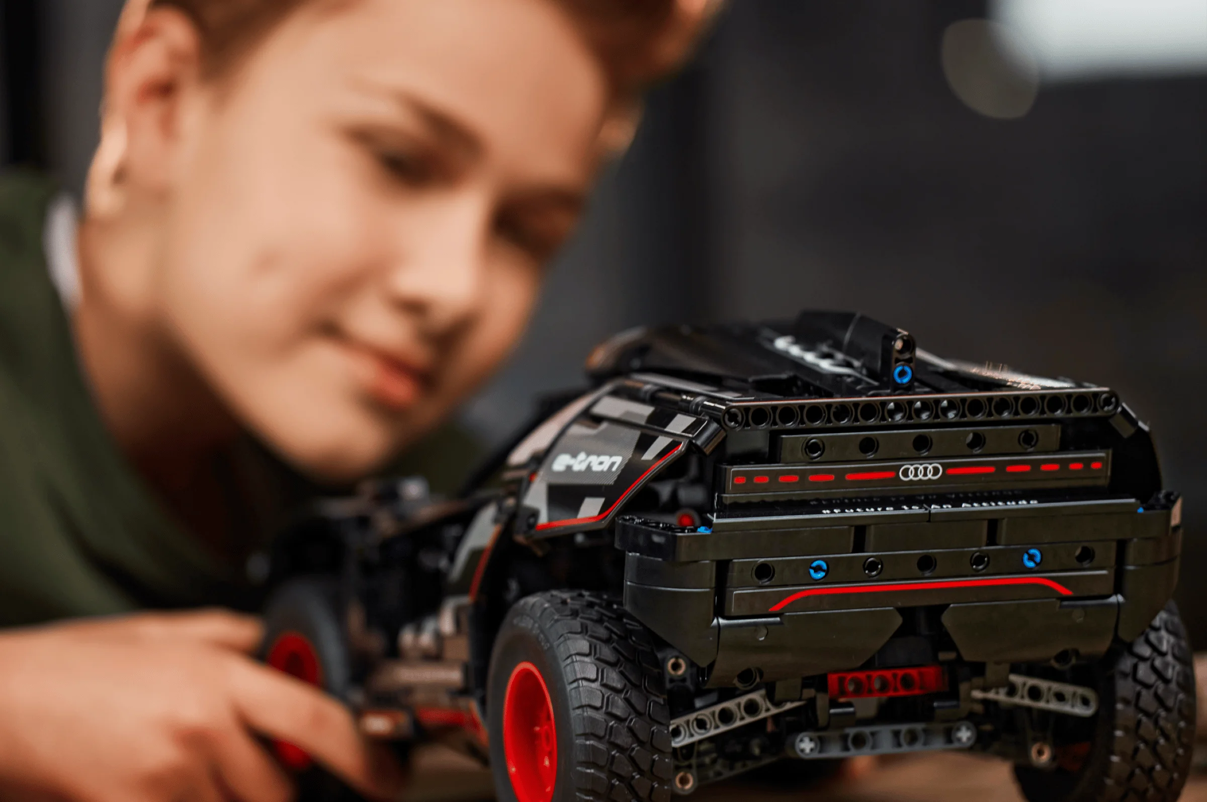 Modelul Audi RS Q e-tron, văzut din spate, cu un copil în fundal, privind cu interes.