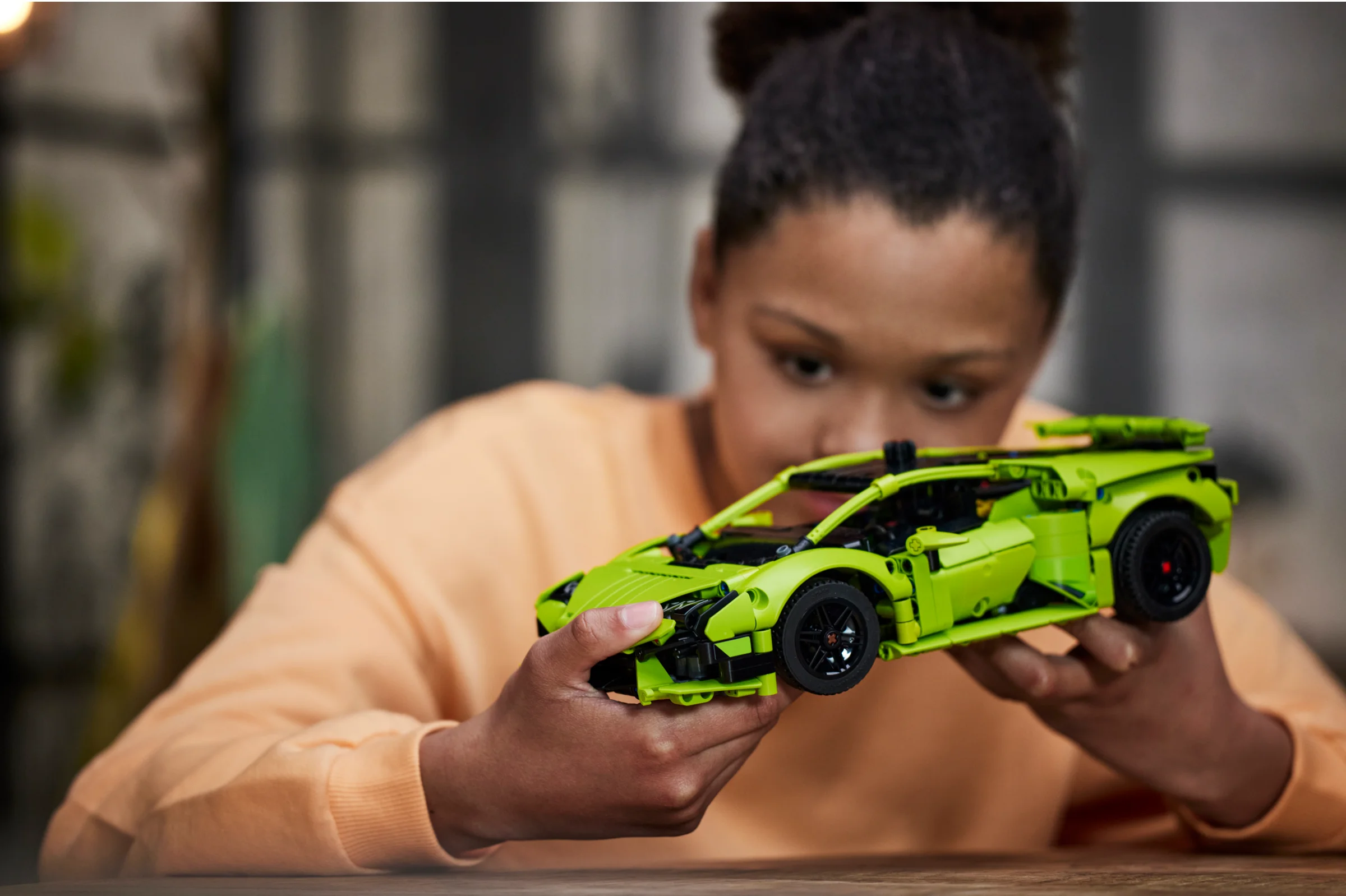 O tânără ține modelul LEGO Technic Lamborghini Huracán Tecnica, admirându-l cu atenție.