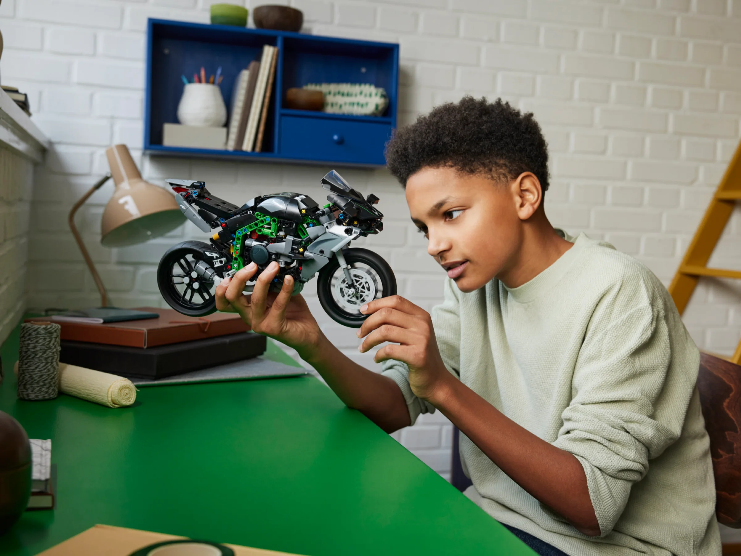 Un băiat admiră motocicleta LEGO Kawasaki Ninja H2R, cu detalii tehnice vizibile.