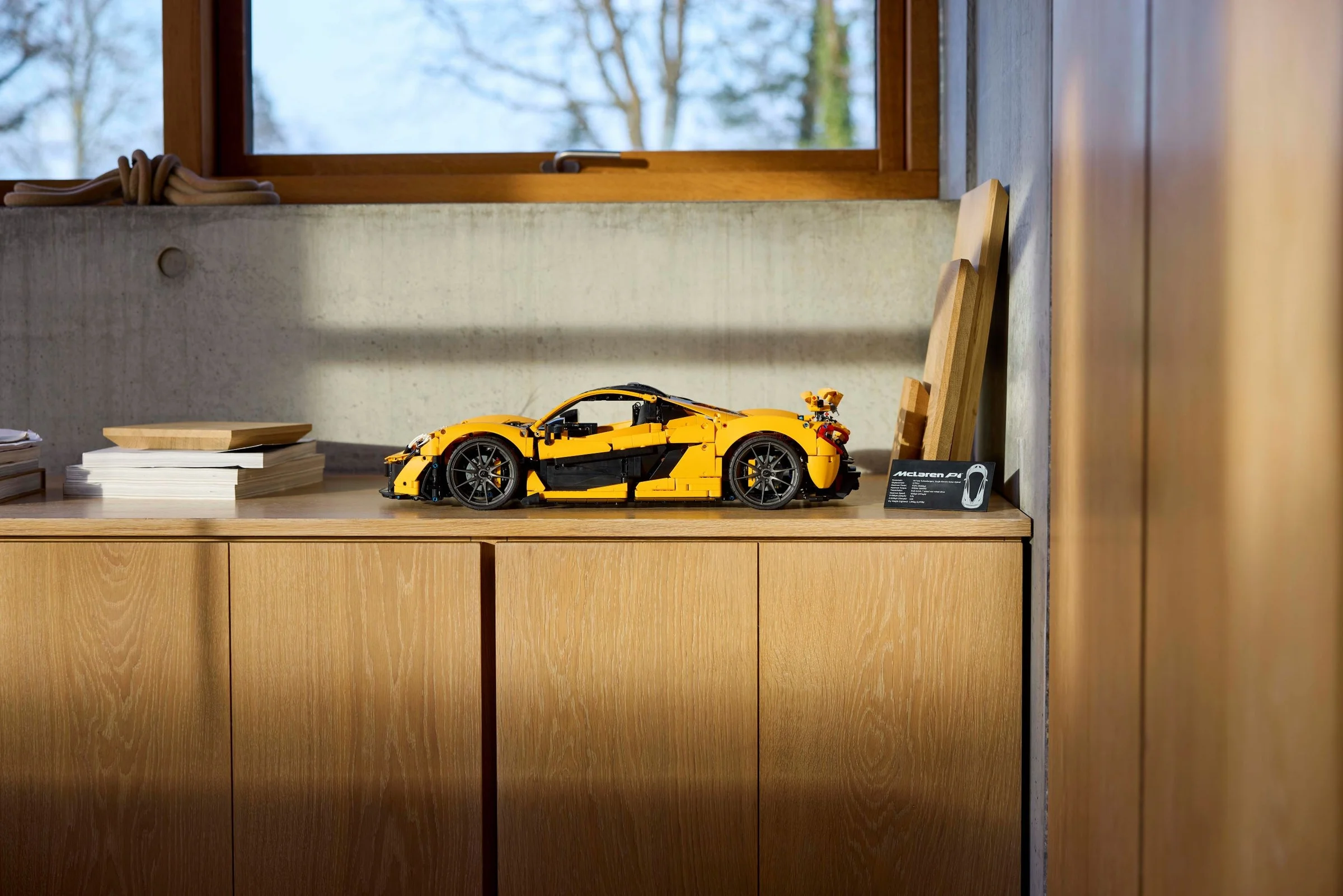 McLaren P1 galben, model LEGO Technic, expus pe o etajeră într-un cadru ambiental.