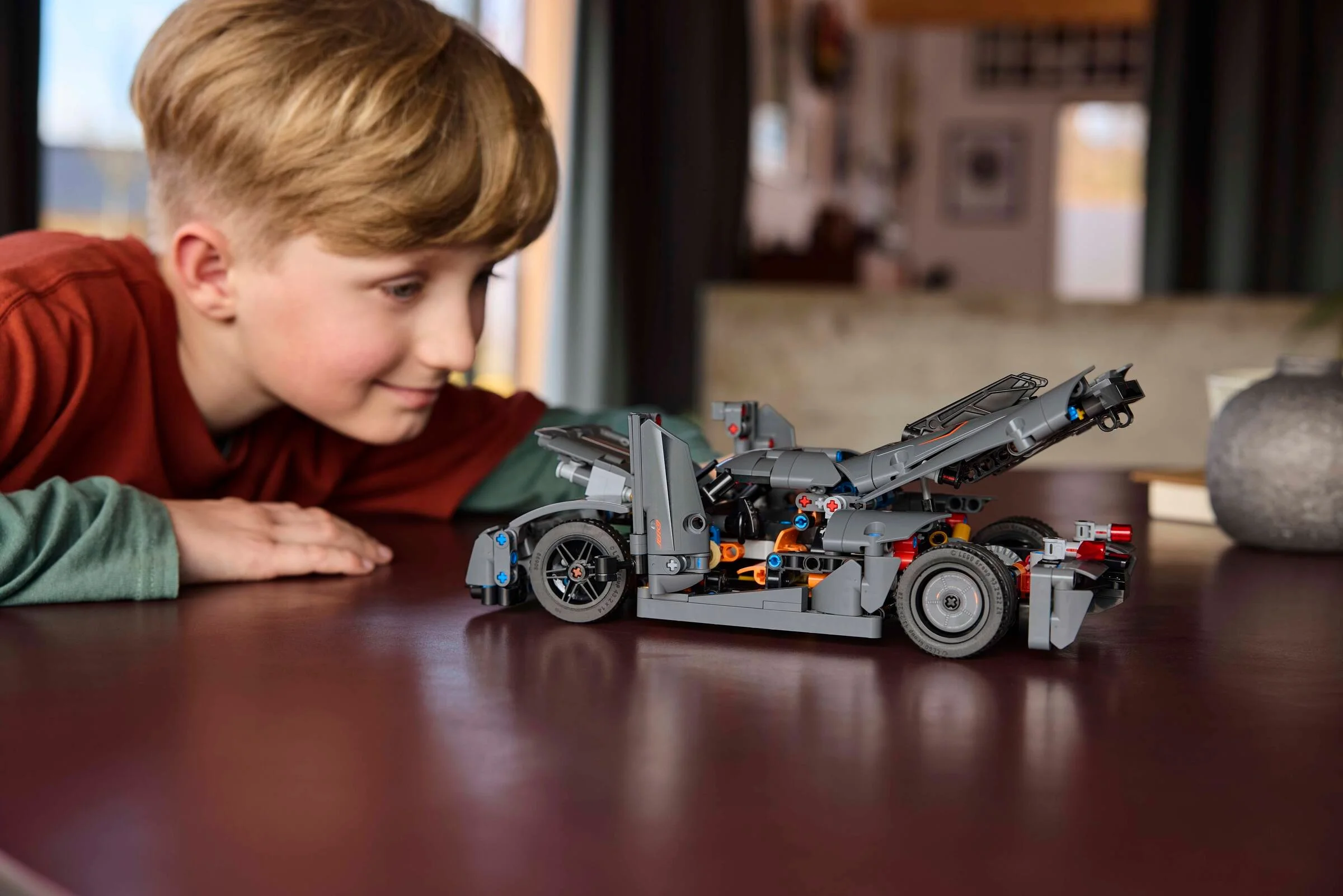 Băiat admirând mașina Koenigsegg Jesko Absolut gri din LEGO Technic, detaliată și complexă.