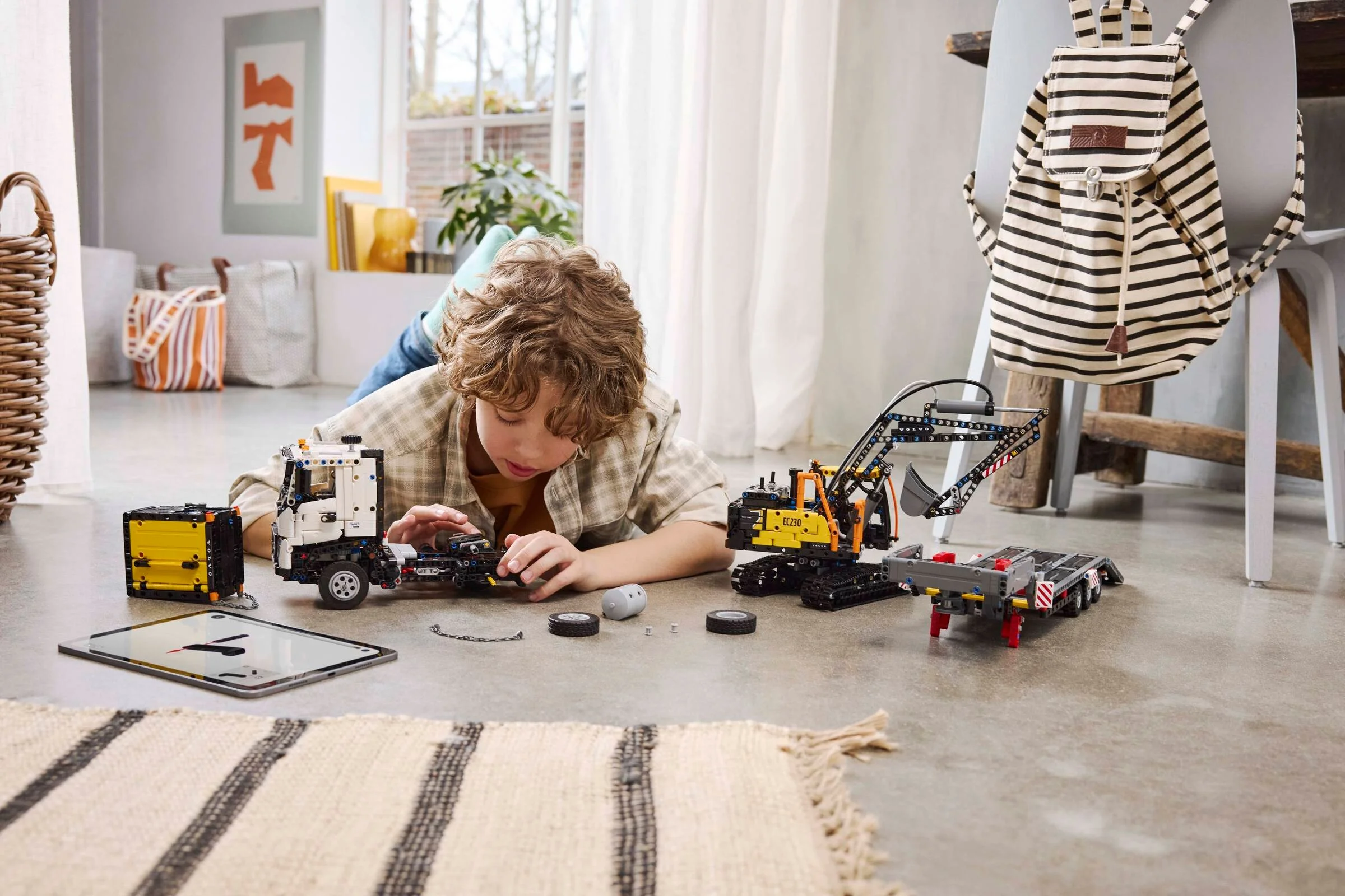 Băiat construind camionul Volvo FMX și excavatorul electric EC230 LEGO Technic.