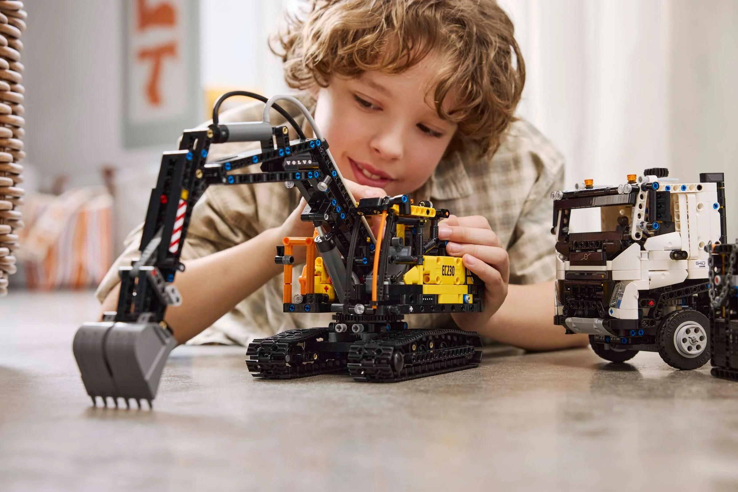 Copil construind setul LEGO Technic Volvo FMX Truck & EC230 Electric Excavator.