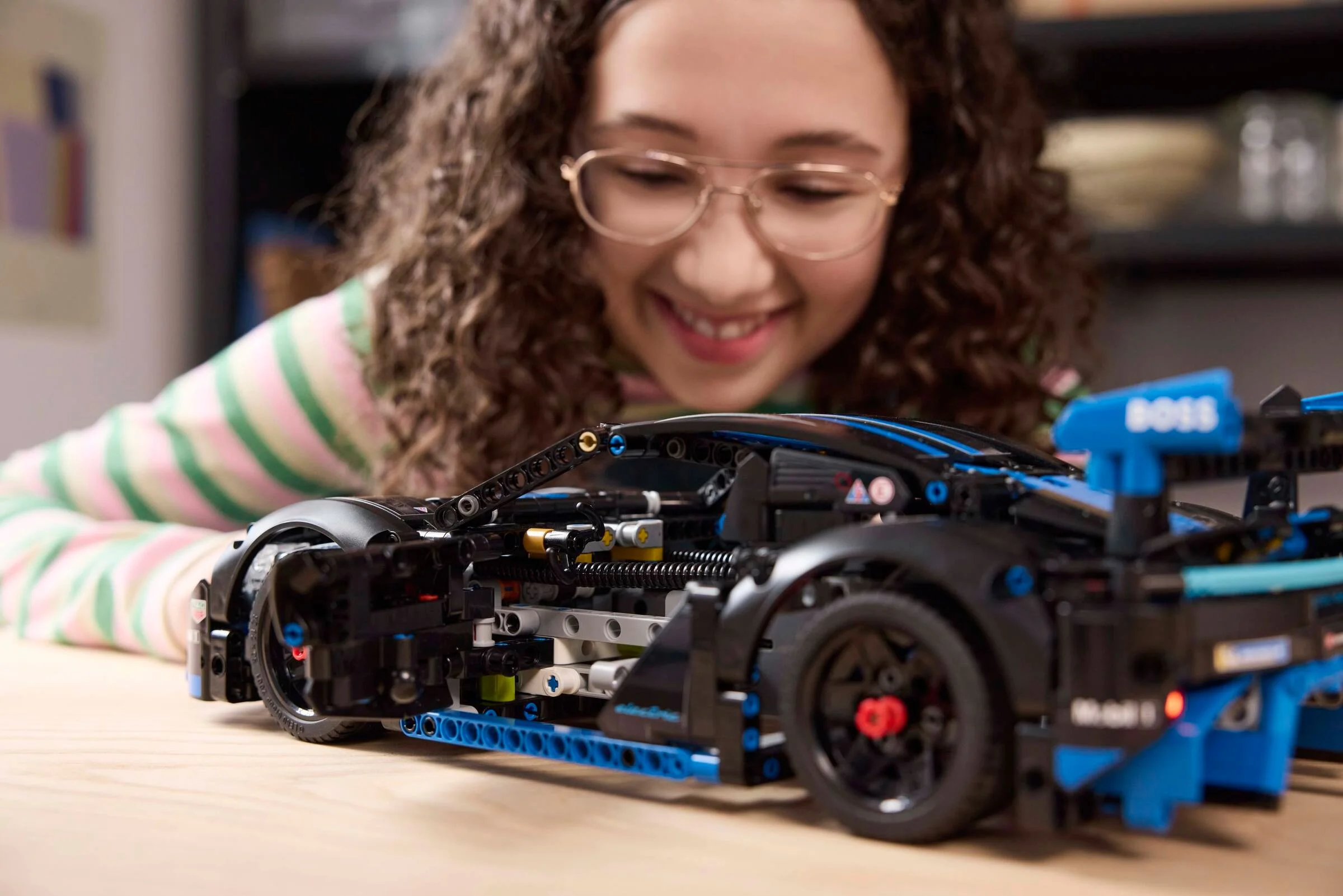 O fată zâmbește admirativ la mașina Porsche GT4 e-Performance din setul LEGO Technic 42176.