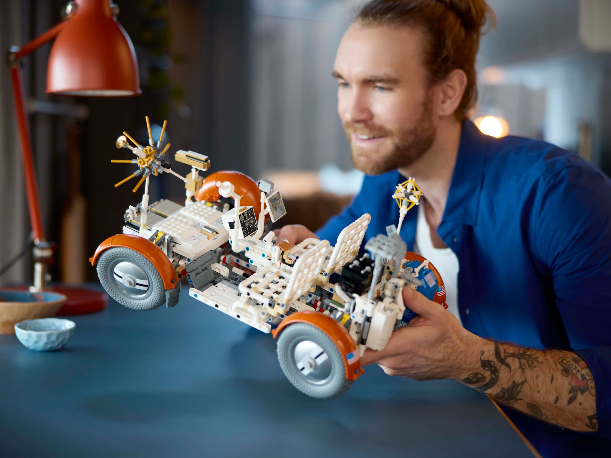 Un bărbat admiră LRV-ul NASA Apollo asamblat, un model Technic complex și detaliat.