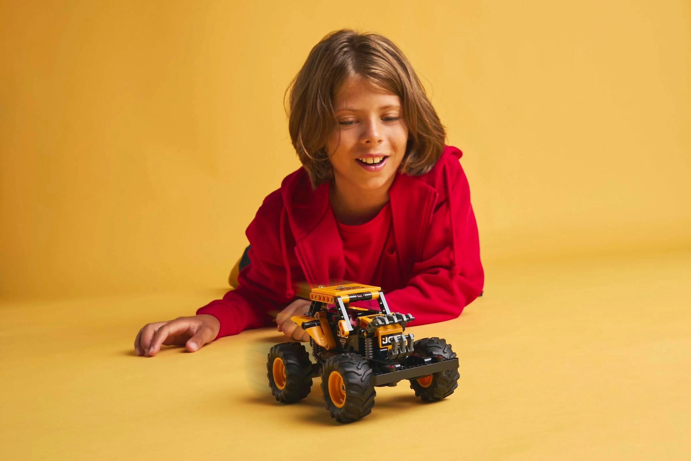Un copil zâmbește către monster truck-ul Digatron. Jucărie atractivă și distractivă.