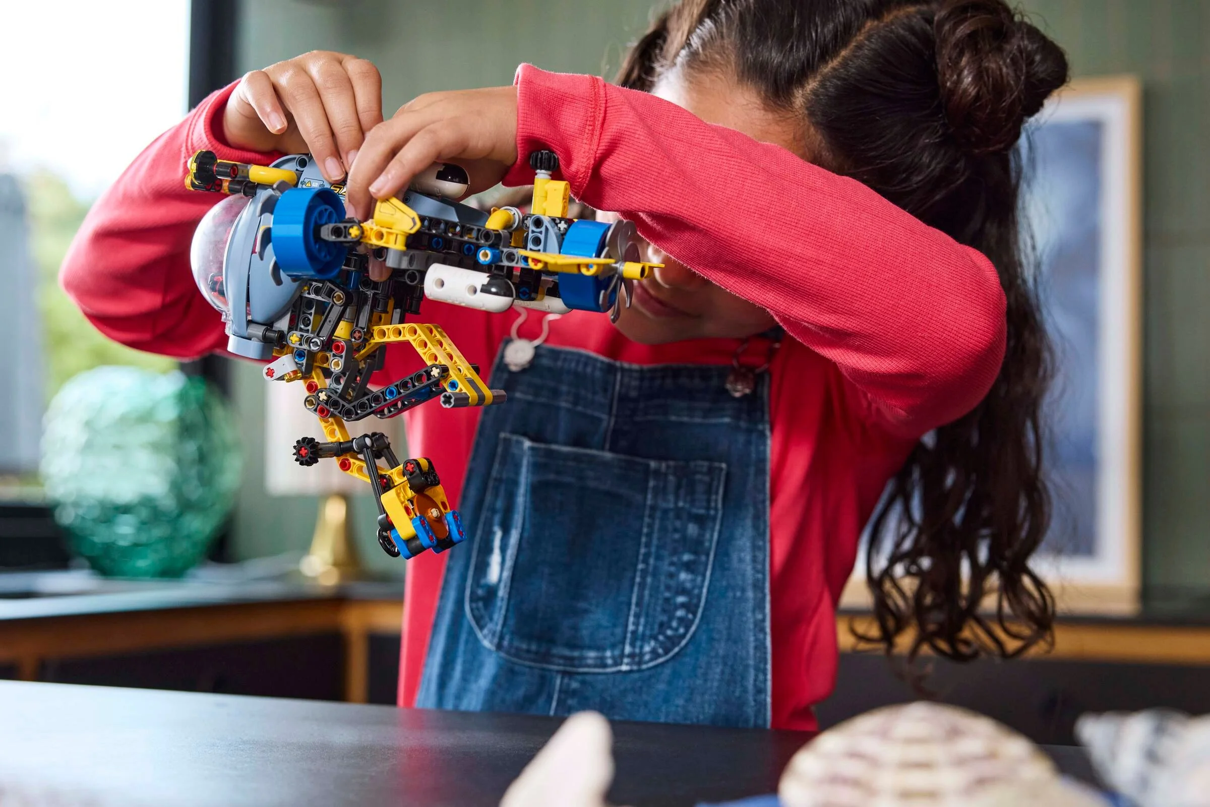 Fetiță construind submarinul de cercetare LEGO Technic. Submarinul este colorat și complex.