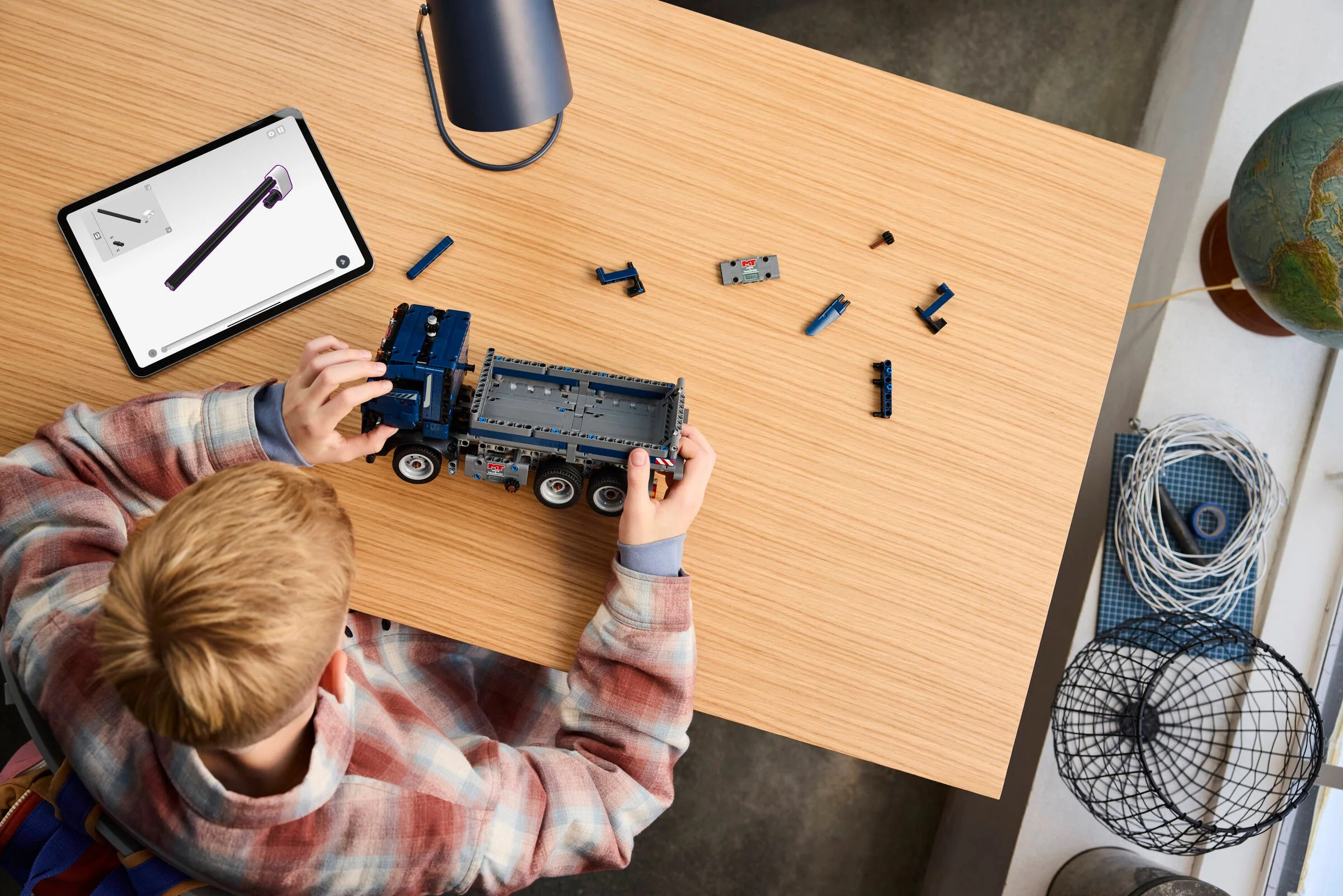 Băiat construind camionul basculant LEGO Technic 42203, folosind instrucțiuni digitale.
