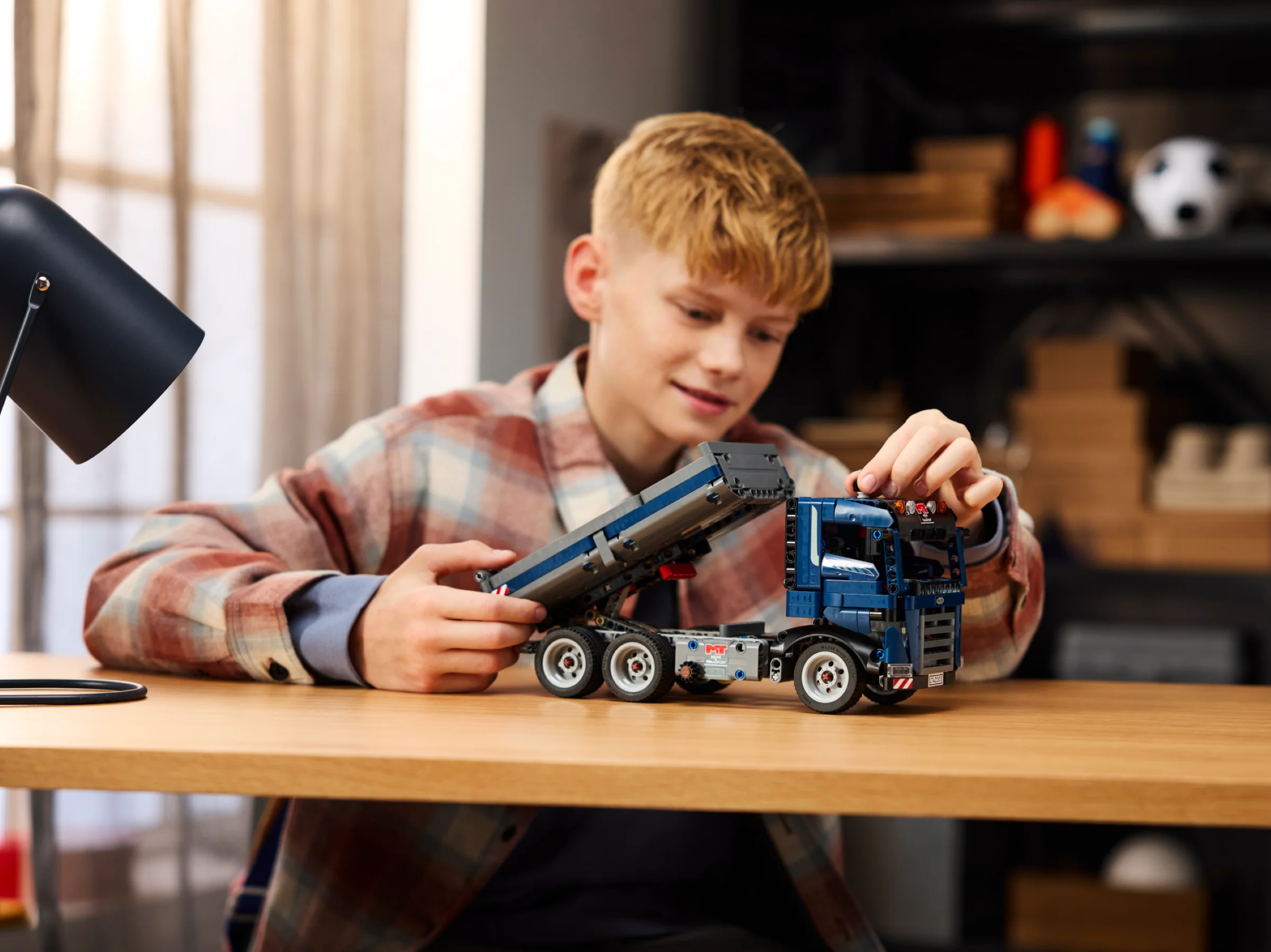 Băiat interacționând cu basculanta LEGO Technic, arătând funcția de ridicare a benei.