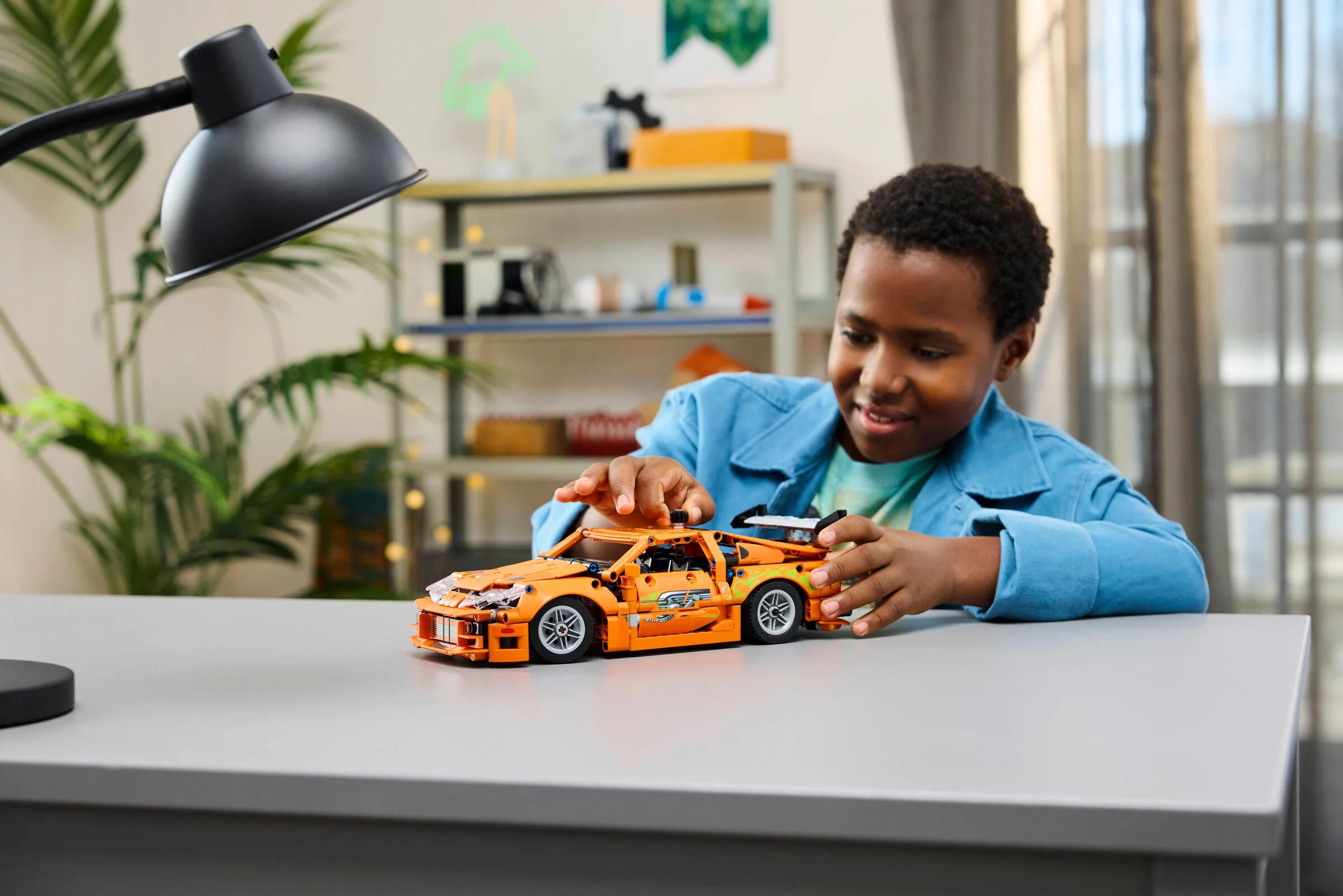 Copil construind modelul LEGO Technic Toyota Supra MK4, concentrare și bucurie.