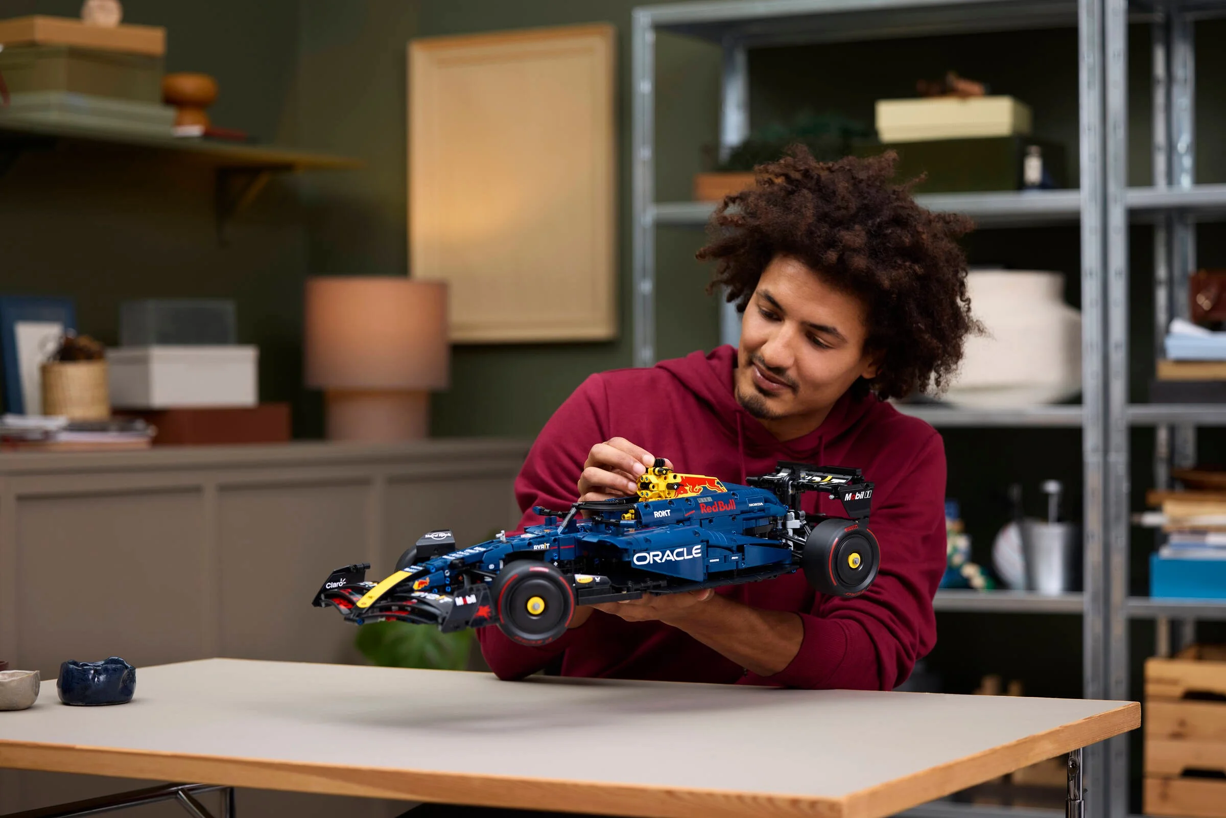 Un adult atașează o componentă la modelul LEGO Technic Oracle Red Bull Racing RB20 F1.