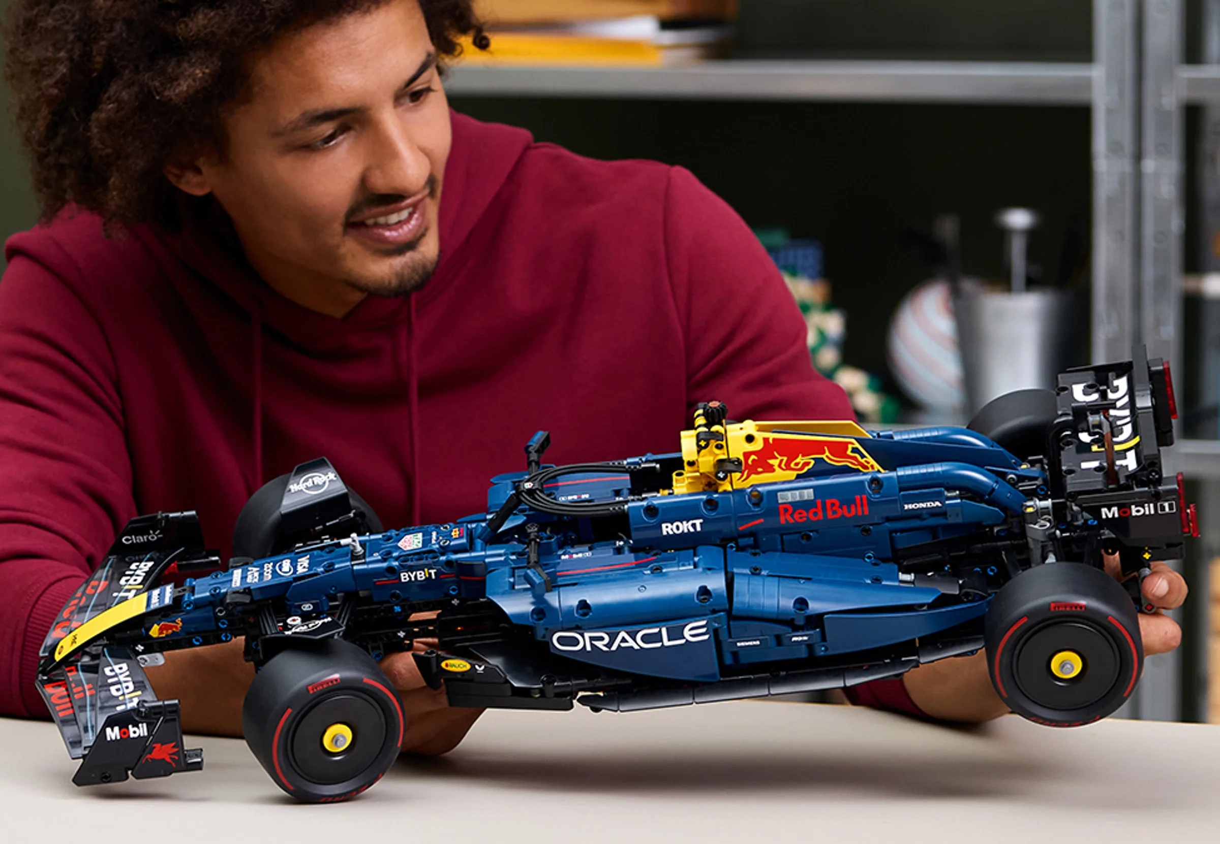 Un tânăr zâmbitor prezintă mașina LEGO Technic Oracle Red Bull Racing RB20 F1.