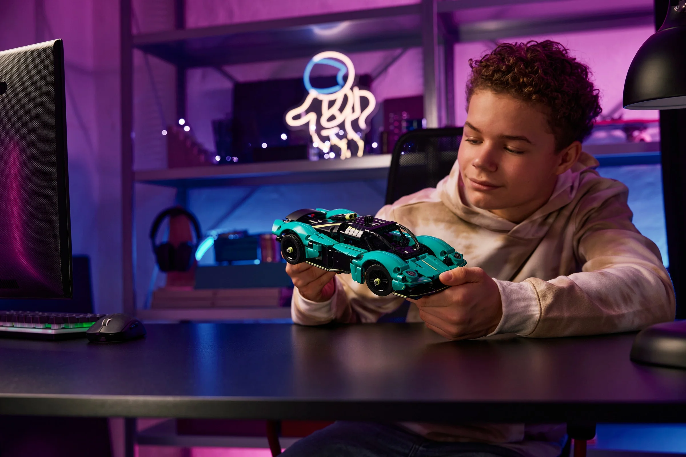 Băiat admirând modelul Aston Martin Valkyrie din LEGO Technic, verde și negru.