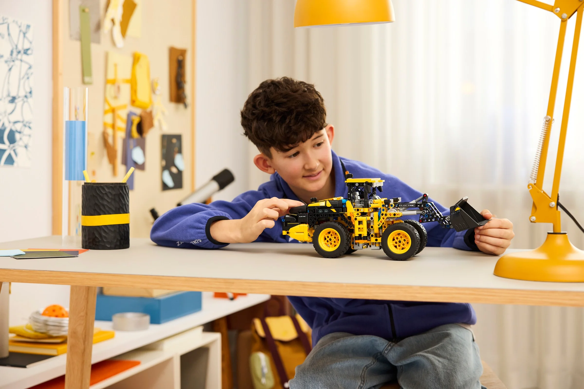Băiat se joacă cu modelul LEGO Volvo L120 Electric Wheel Loader. Jucărie detaliată.
