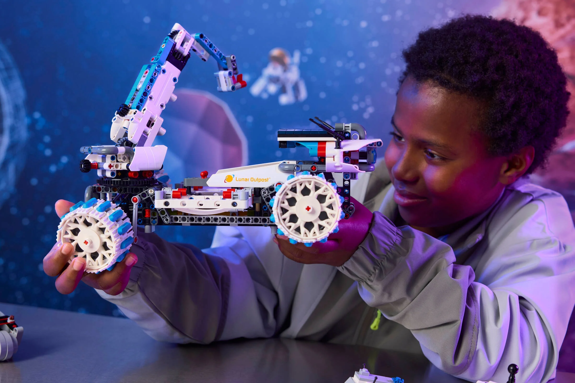 Un copil ține roverul lunar LEGO 42211, evidențiind brațul robotic și roțile unice.