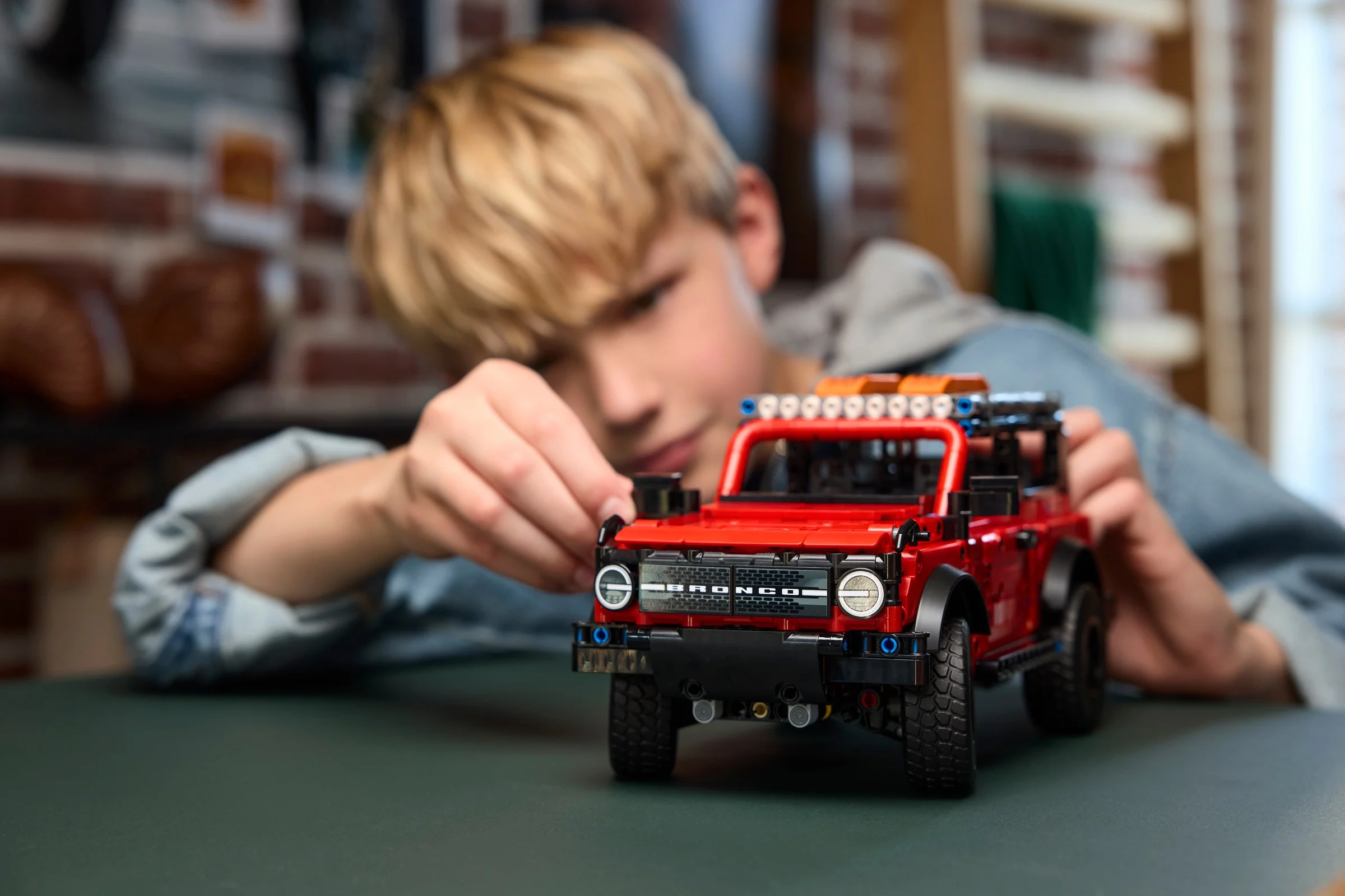 Imagine cu un copil interacționând cu modelul Ford Bronco SUV LEGO Technic.