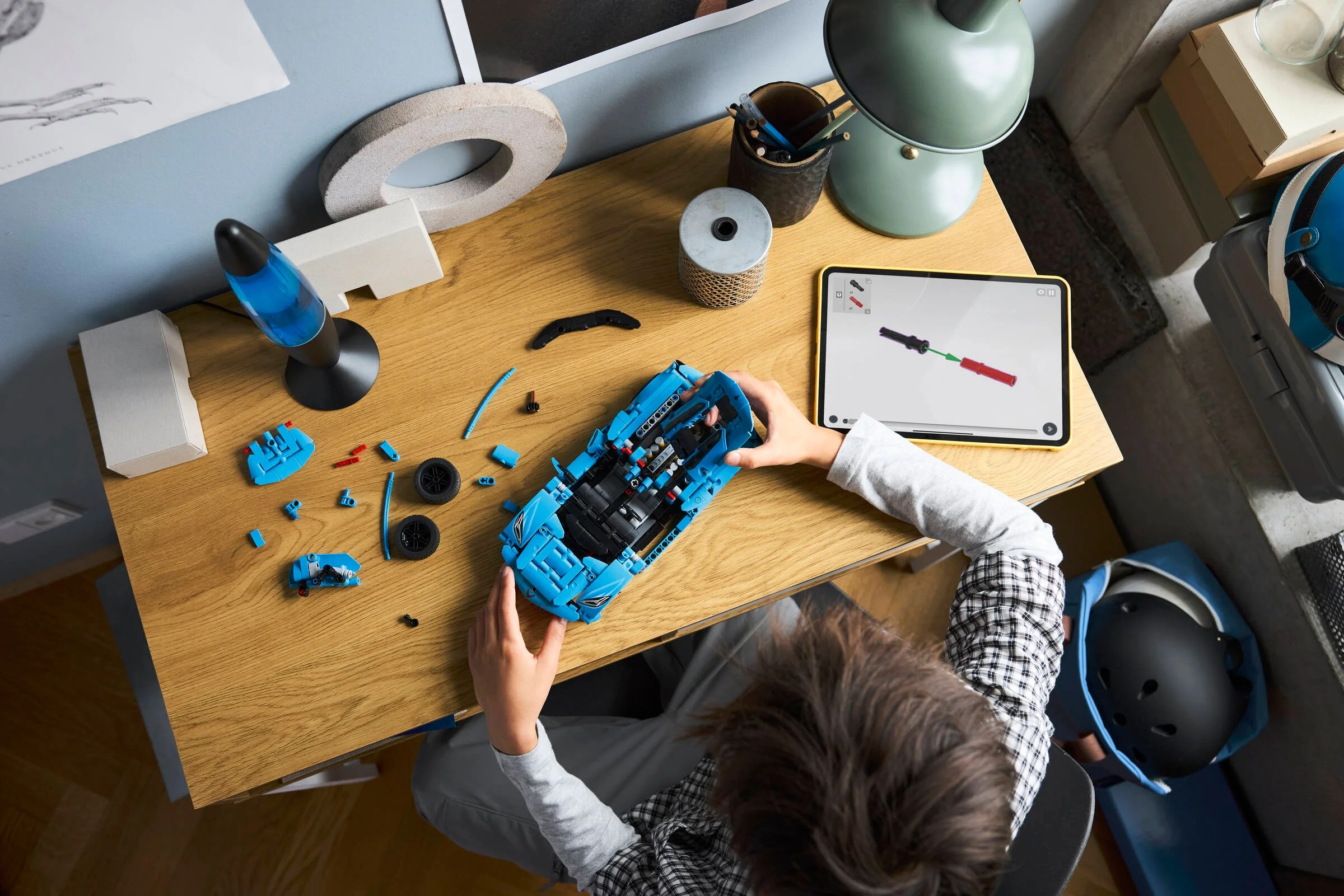 Un copil construiește Corvette Stingray folosind instrucțiuni pe tabletă. Asamblare în desfășurare.