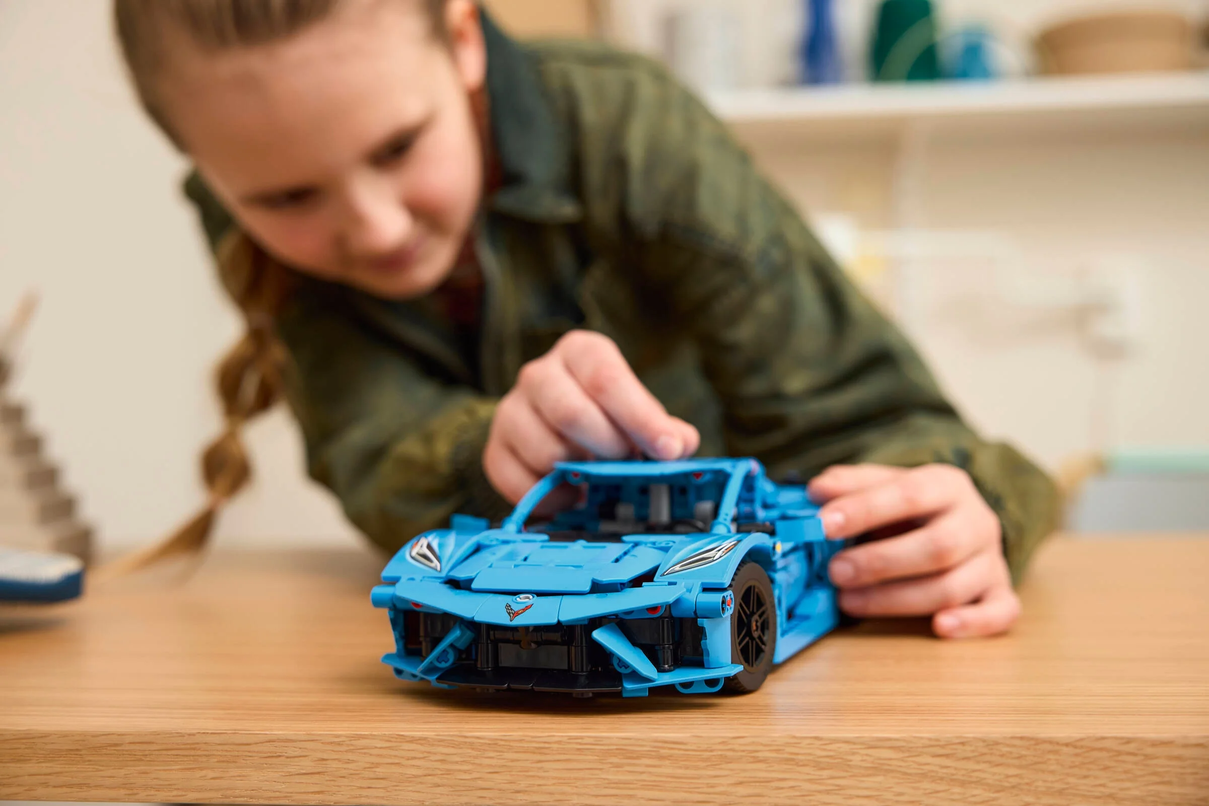 Fetiță construind modelul LEGO Chevrolet Corvette Stingray albastru, concentrare pe detalii.