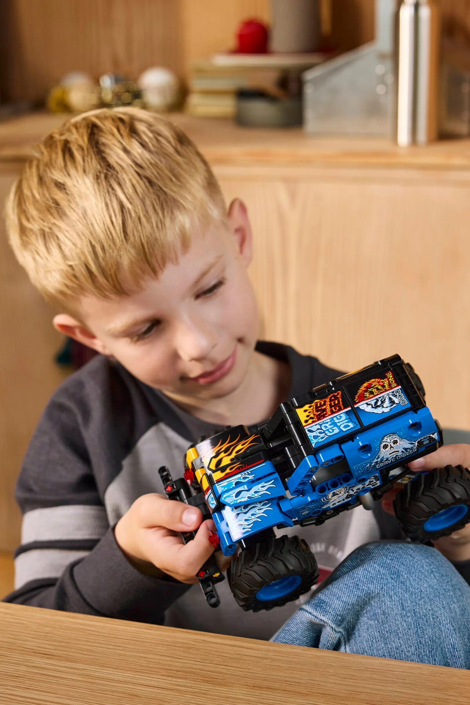Băiat admirând modelul LEGO Technic Monster Jam Grave Digger, o experiență captivantă.