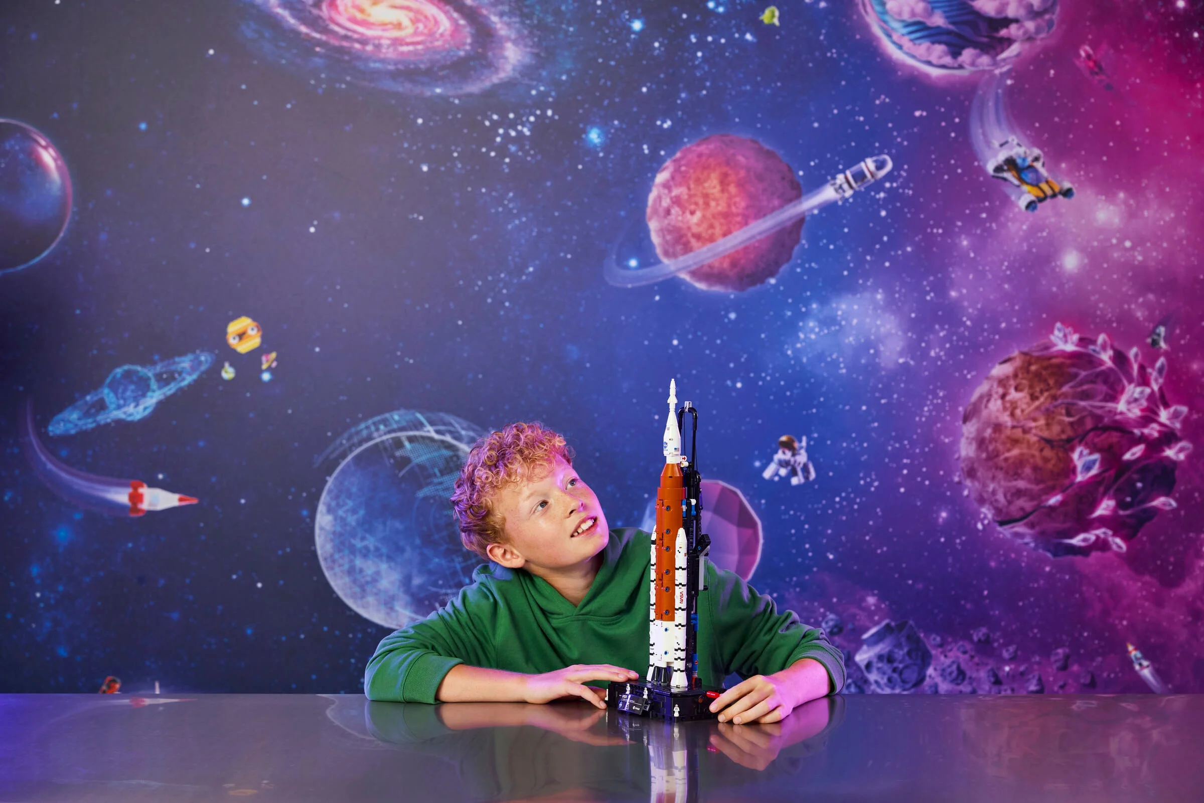 Băiat admirând racheta NASA Artemis Space Launch System construită din LEGO.