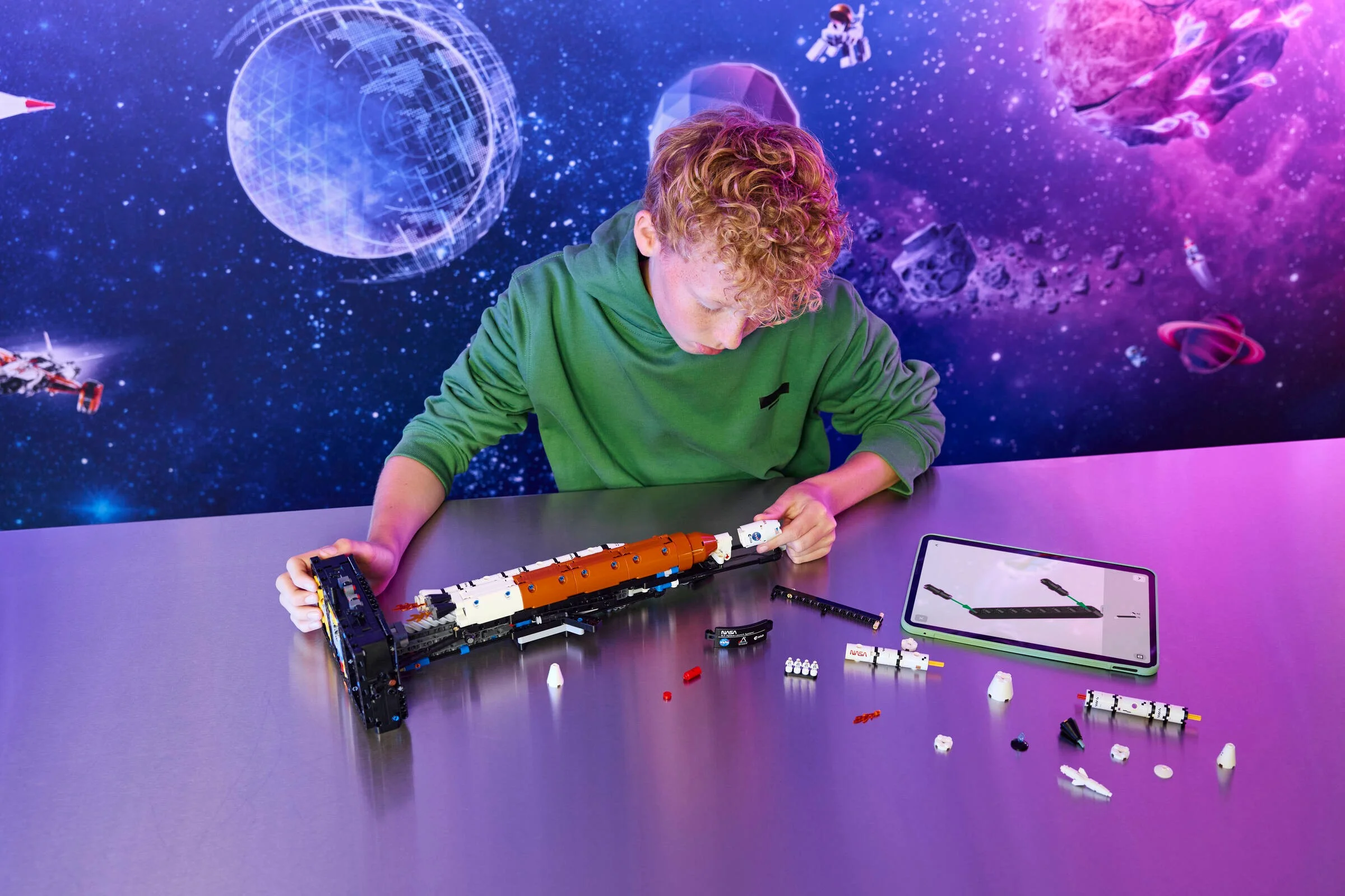 Un băiat construiește racheta NASA Artemis Space Launch System din LEGO Technic.