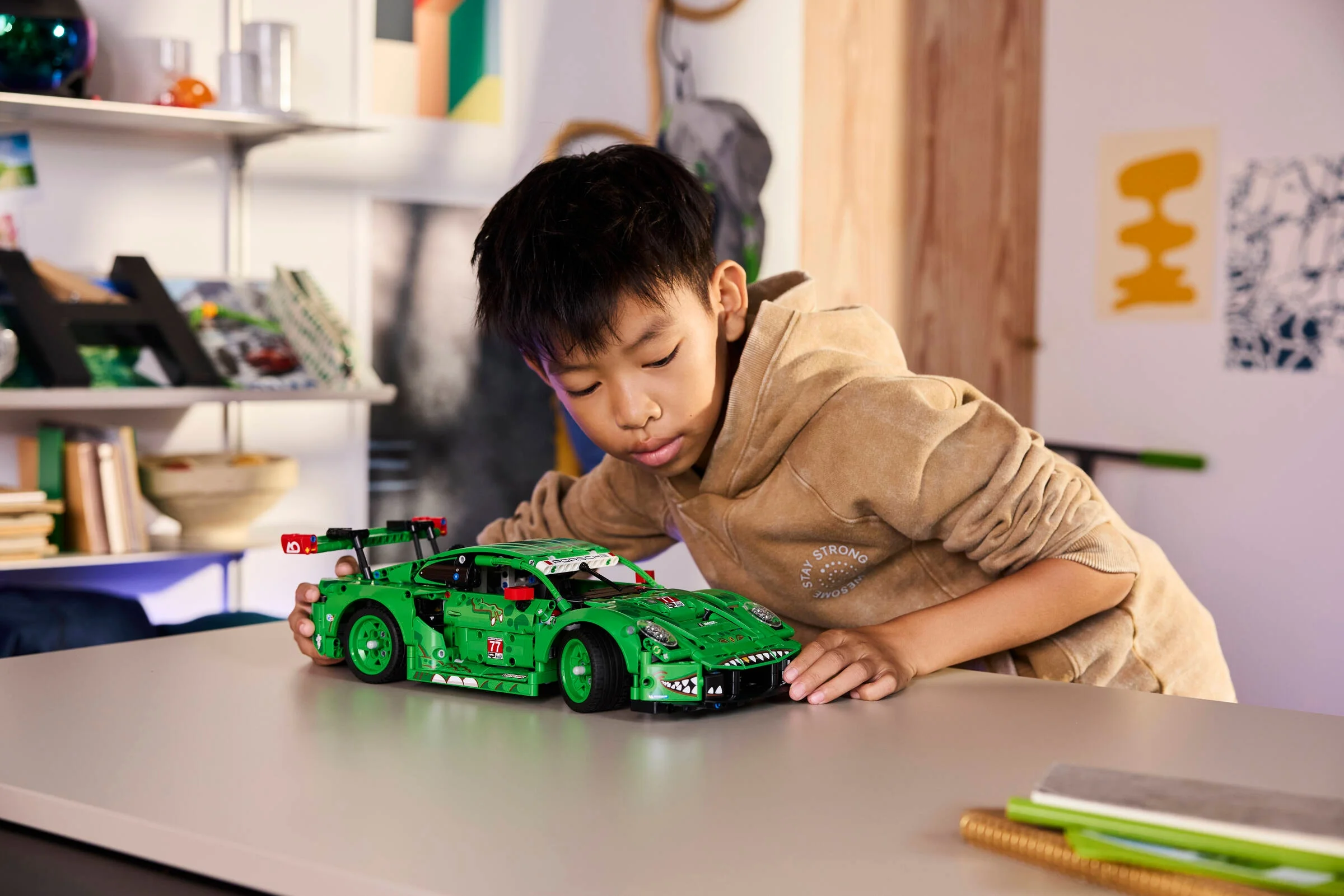 Băiat admirând modelul Porsche 911 GT3 R verde REXY AO Racing.