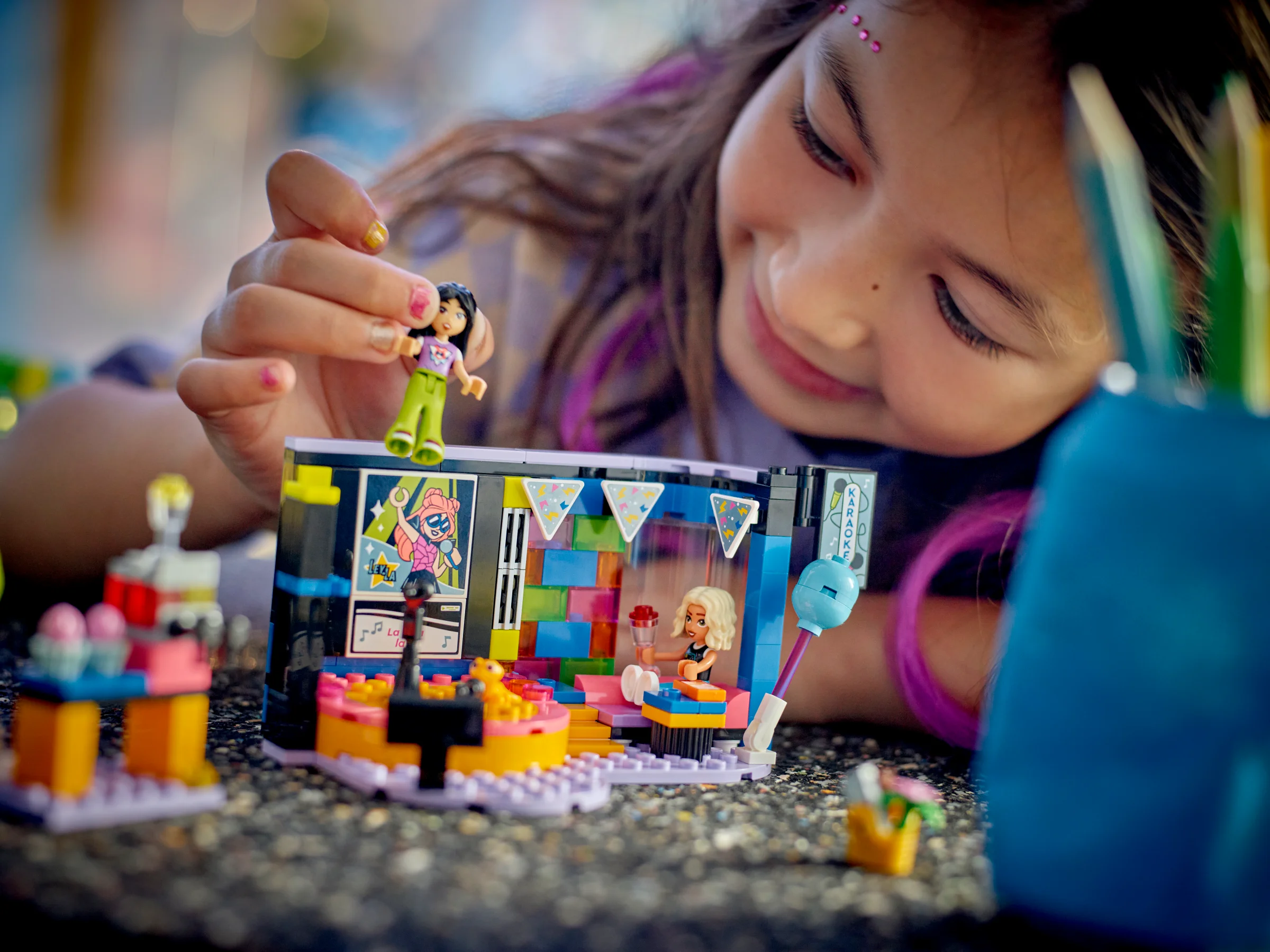 Fetiță se joacă cu setul LEGO Friends Karaoke, arătând minifigurina. Copii și distracție!
