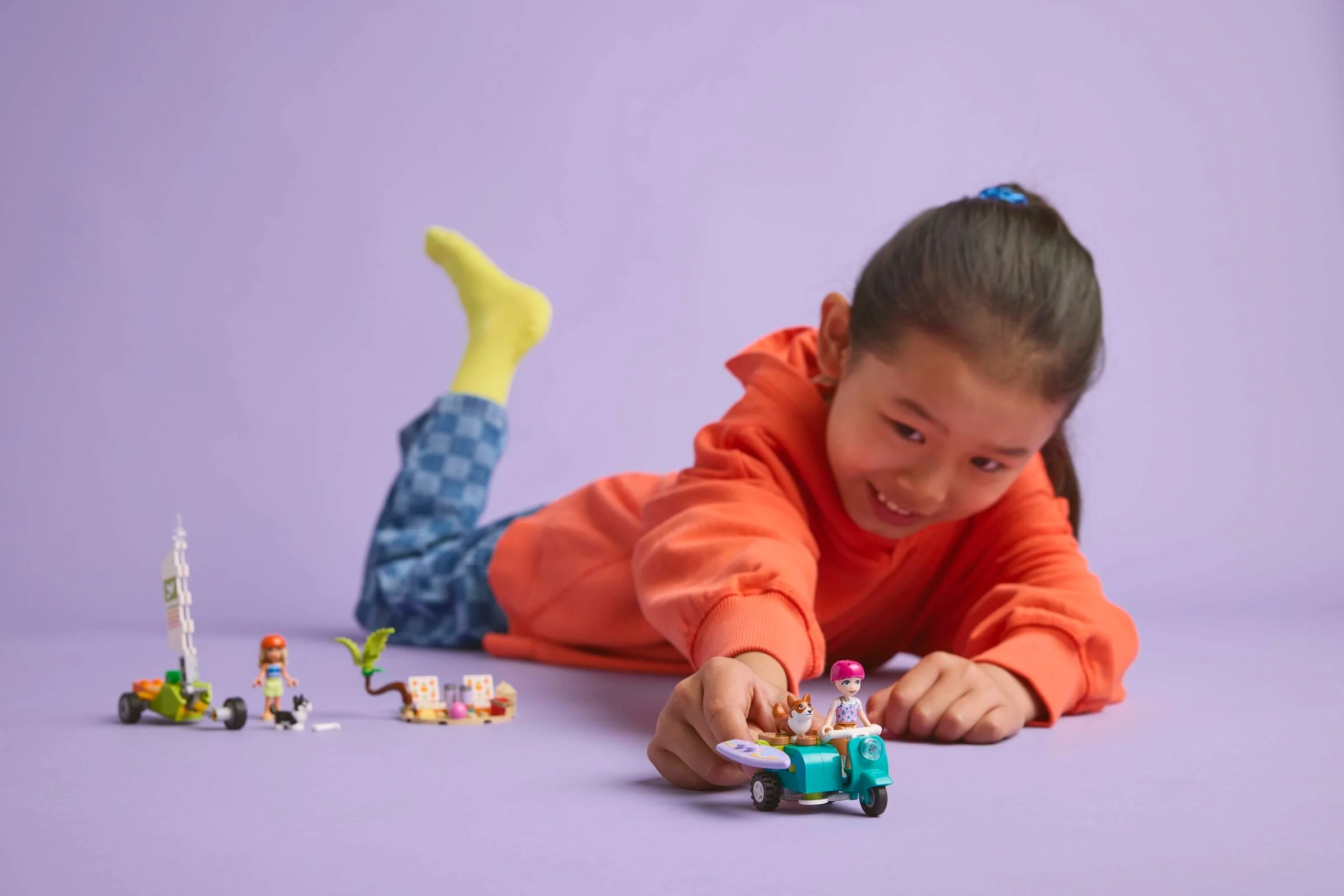 Fată jucându-se cu setul LEGO Surfing Dogs și Scooter Adventure. Zâmbete și distracție!