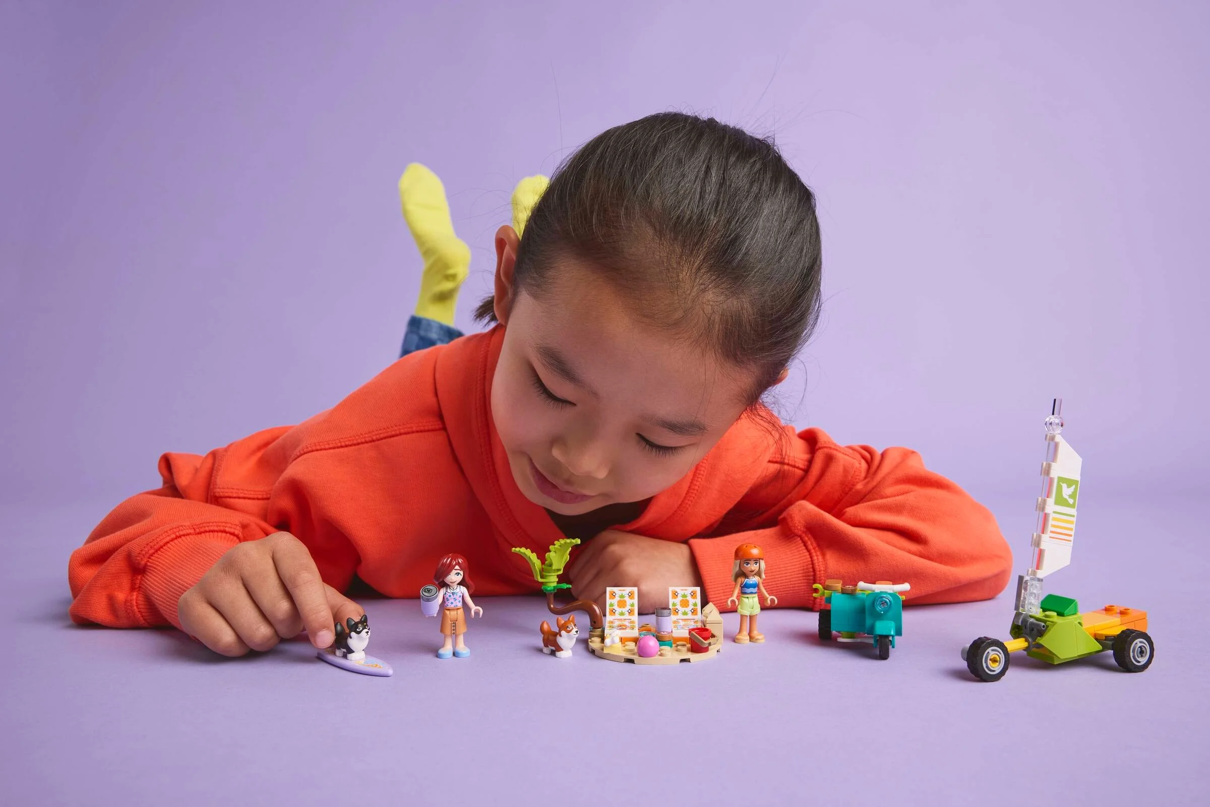 O fetiță se joacă cu setul LEGO 42641, „Câini surferi și aventură cu scuterul”.
