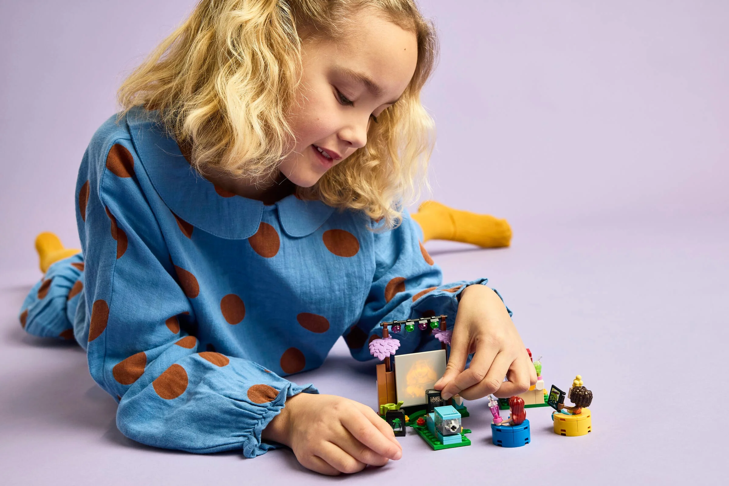 O fetiță construiește setul LEGO Prieteni Seara de Film. Modelul este aproape gata.
