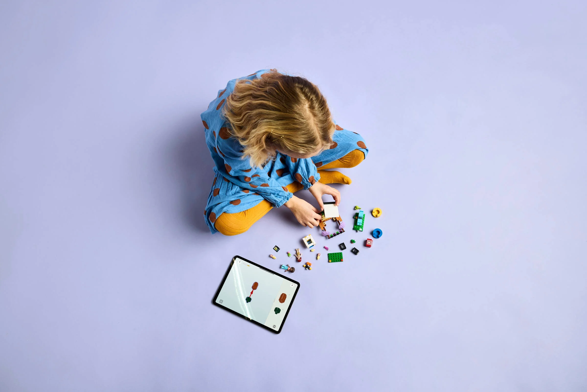 Fetiță construind setul LEGO Friends 42642 cu ajutorul unei tablete.