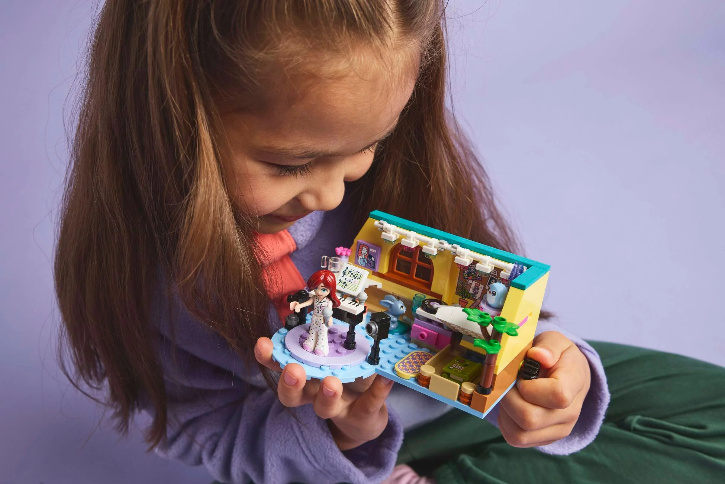 O fetiță se uită atent la setul LEGO 42647, camera lui Paisley, un model colorat și detaliat.