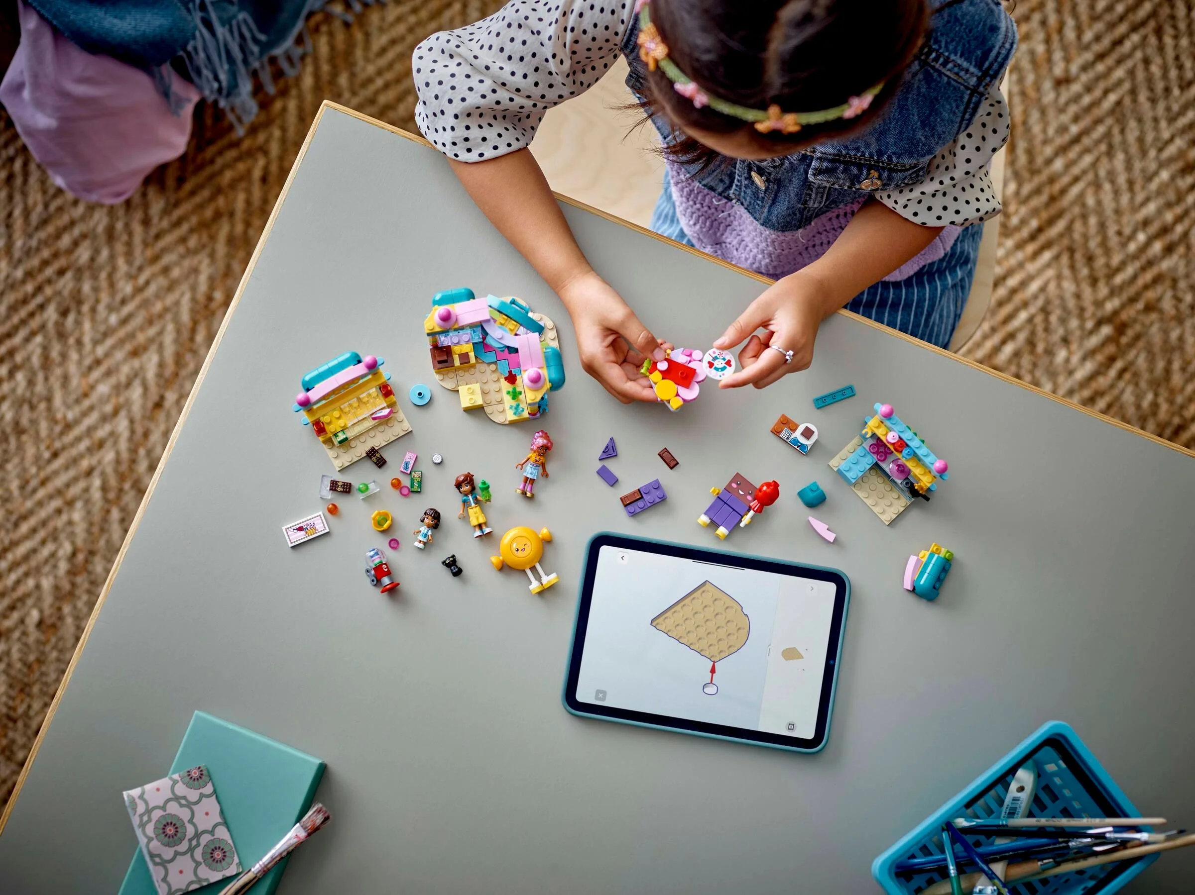 O fată construiește setul LEGO Friends 42649, magazinul de dulciuri, urmând instrucțiunile pe o tabletă.