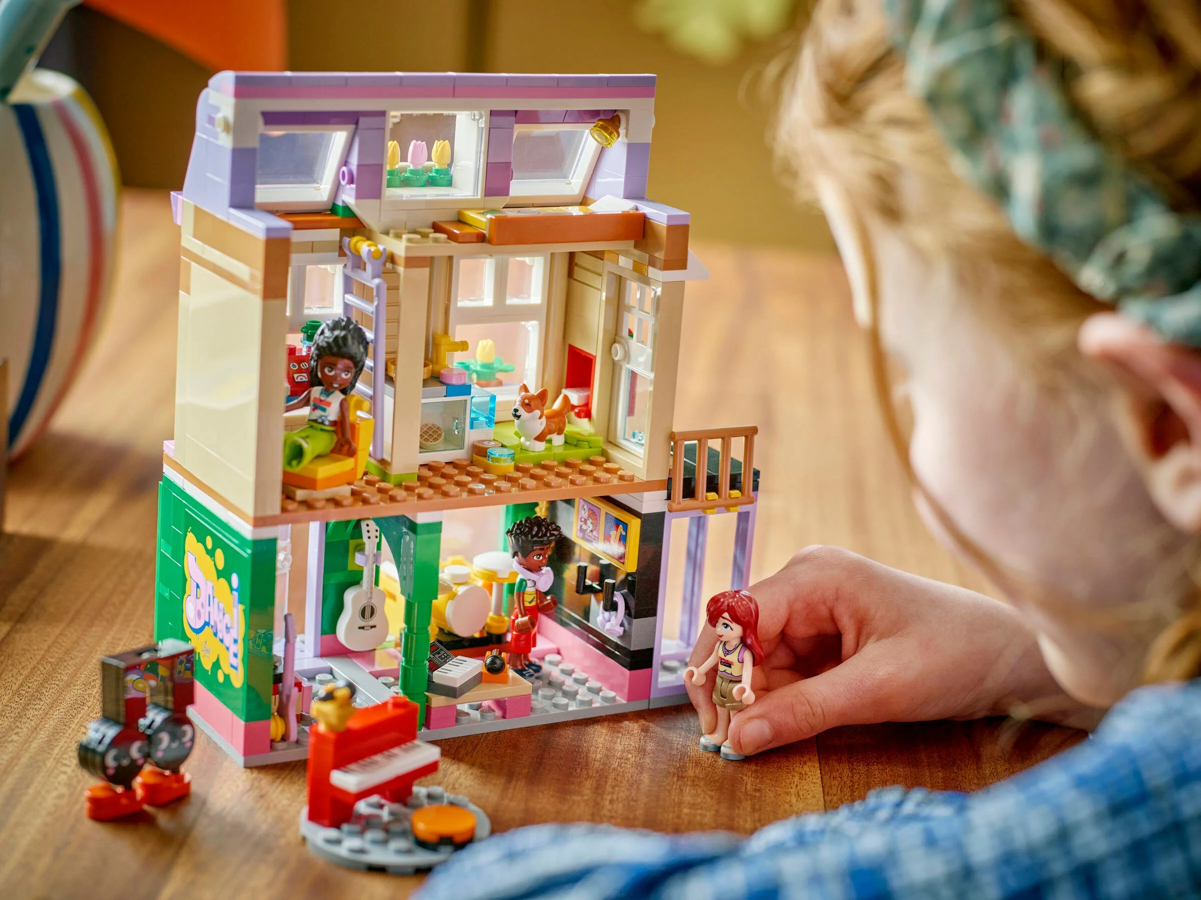 Copil se joacă cu setul LEGO Friends 42653, Magazin de Muzică și Apartament.
