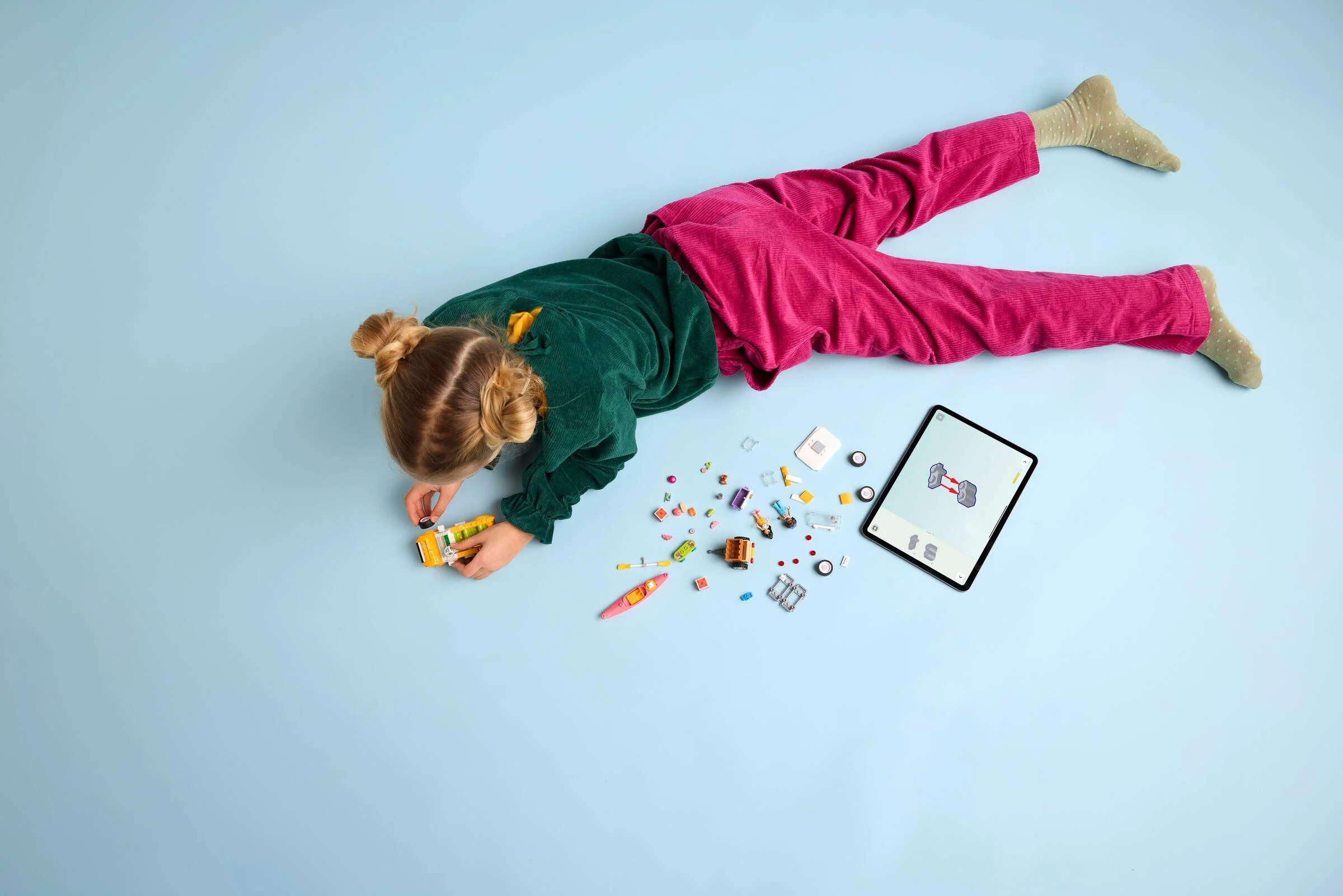 Copil construind mașina de călătorie LEGO Friends, folosind instrucțiuni digitale pe tabletă.
