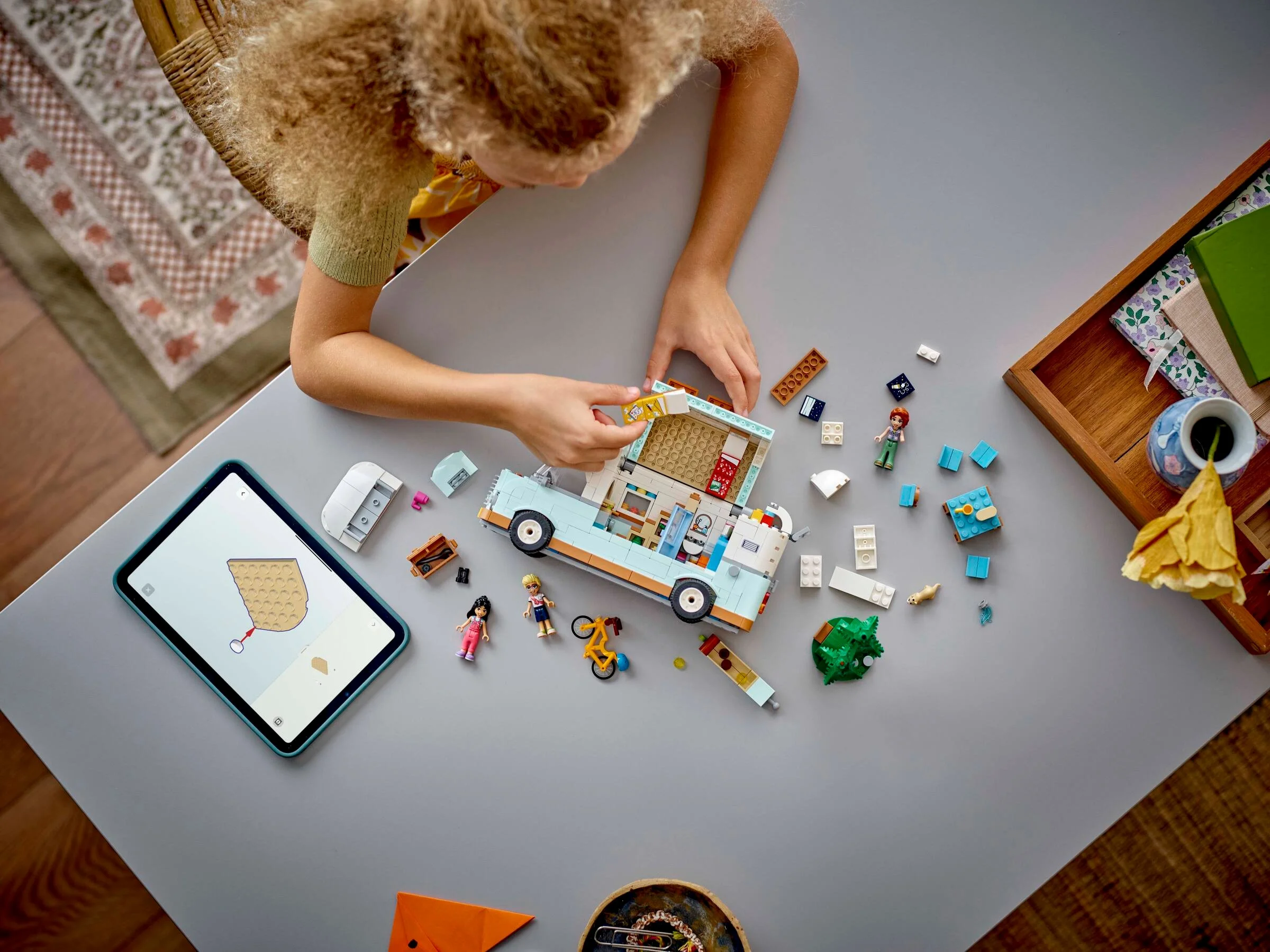 Copil construind rulota LEGO Friends, urmând instrucțiunile de pe tabletă.