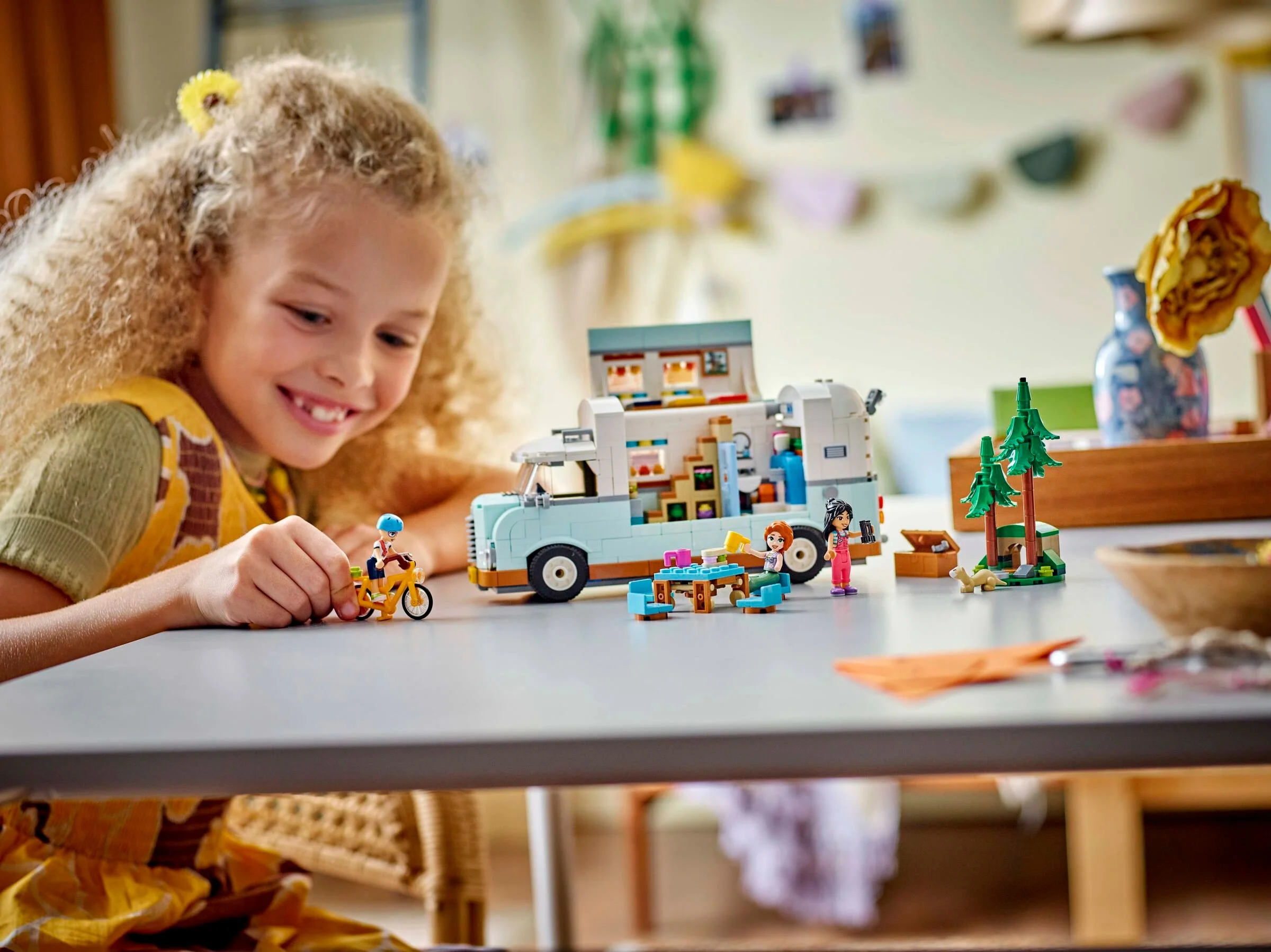 O fetiță se joacă cu camperul LEGO Friends, explorând aventuri prietenoase.