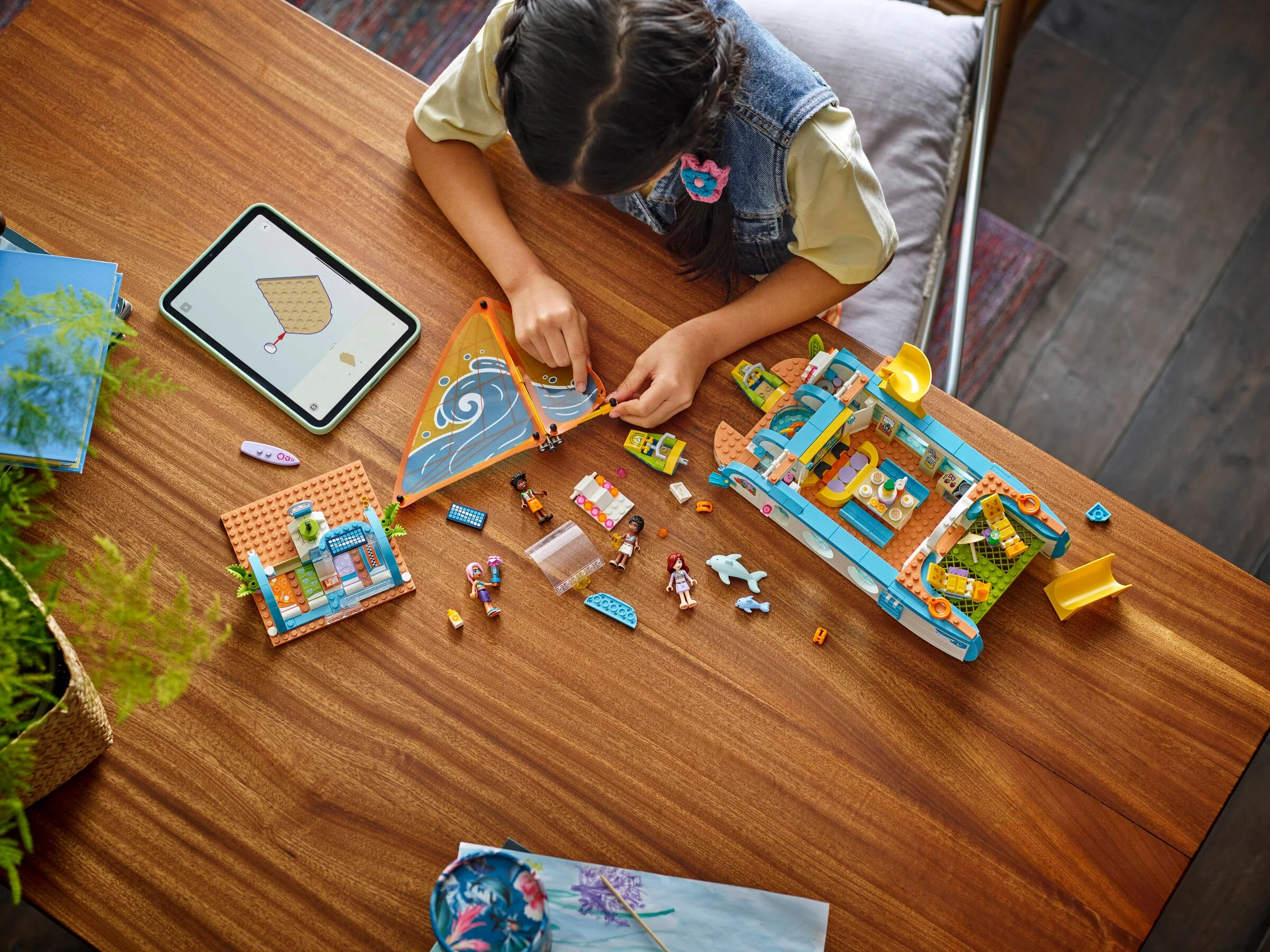 O fetiță construiește barca de călătorie LEGO Friends, urmând instrucțiunile de pe tabletă.
