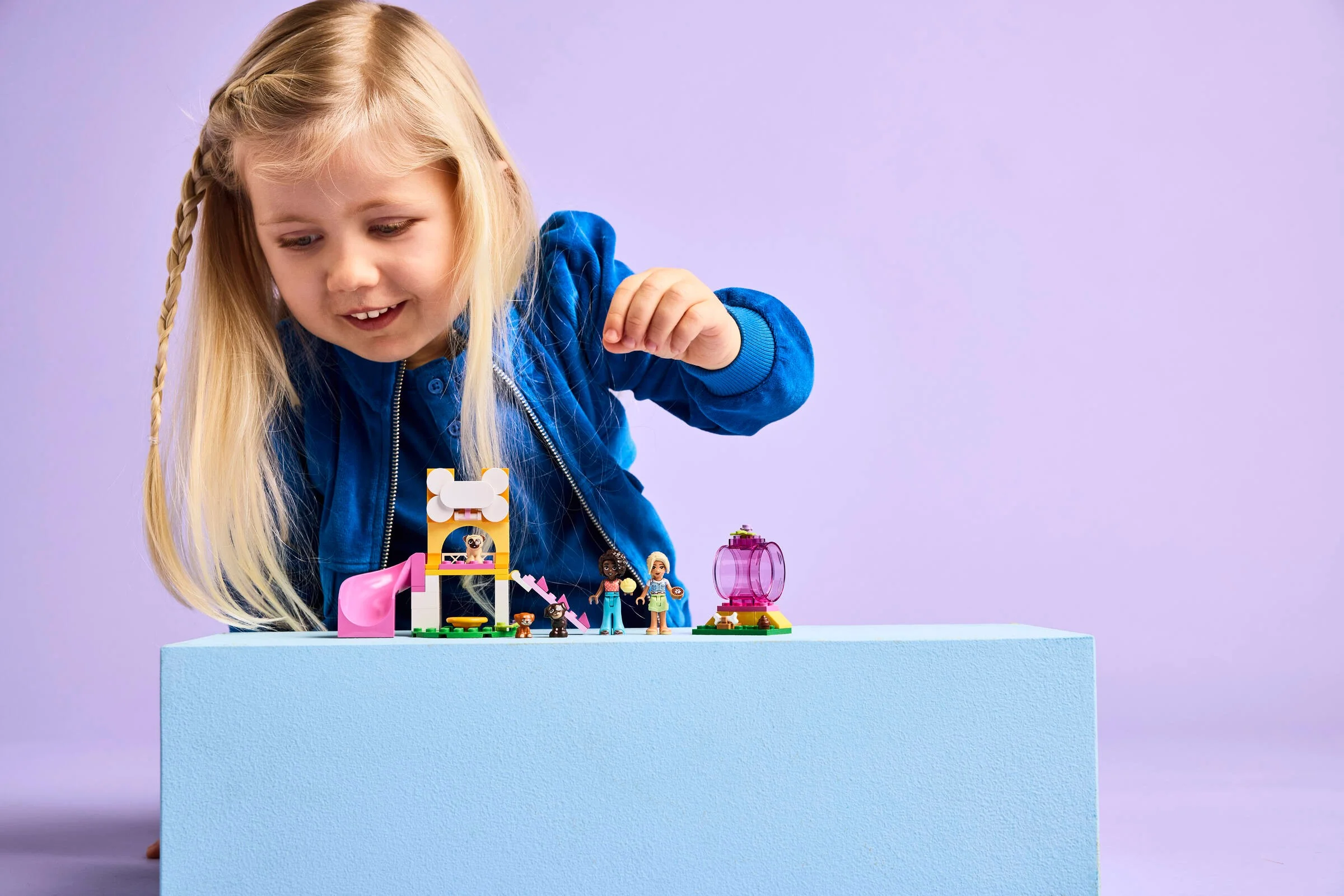 Fetiță se joacă cu setul LEGO Friends 42665, un loc de joacă pentru căței.