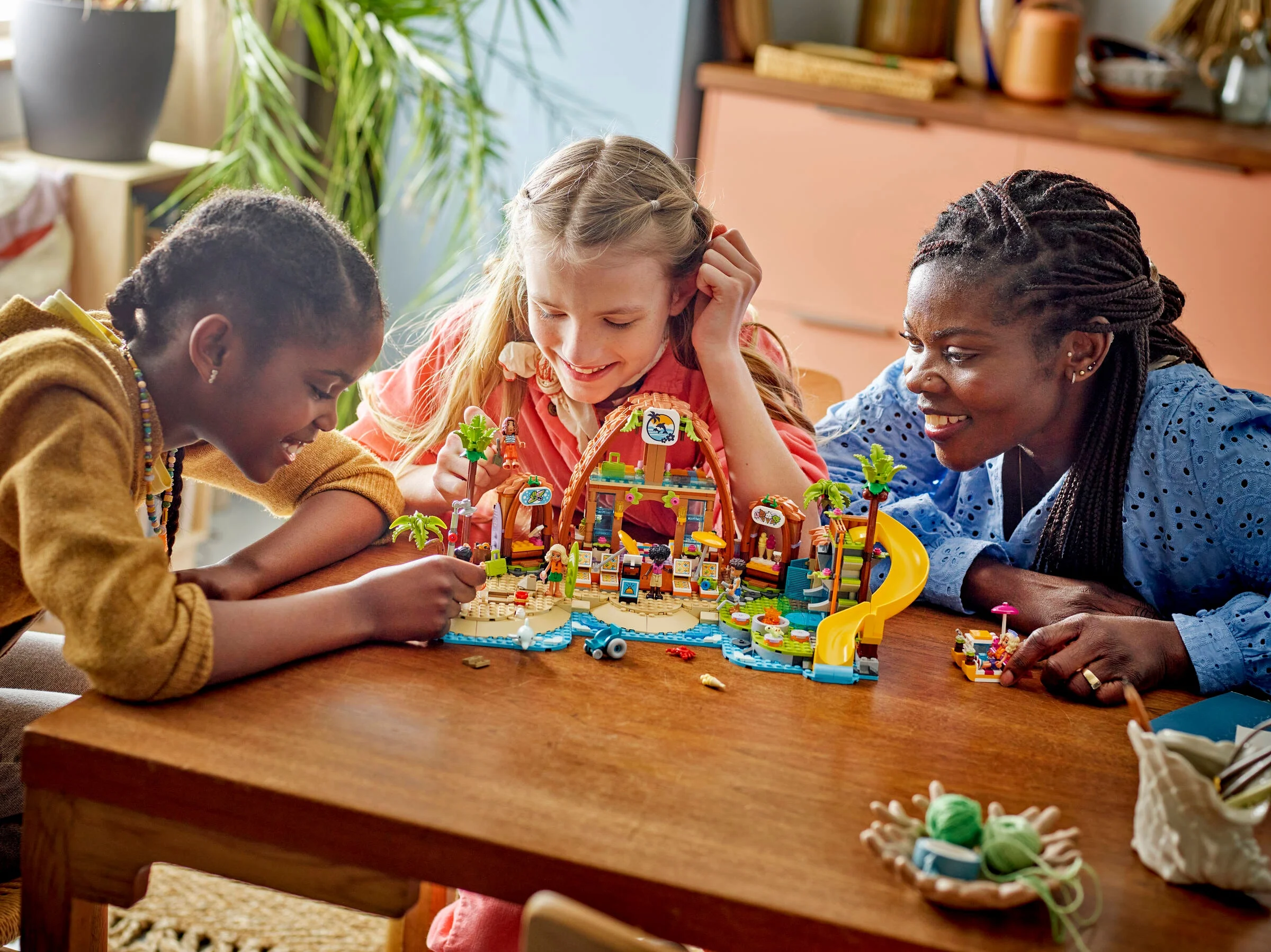 O familie se bucură construind setul LEGO Friends Stațiune pe plajă. Zâmbete și relaxare la soare.