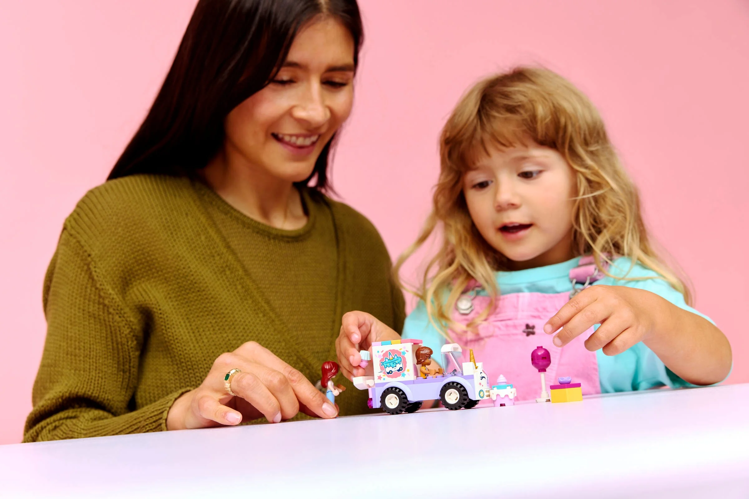 O mamă și fiica se joacă cu mașina de livrare prăjituri unicorn LEGO Friends.