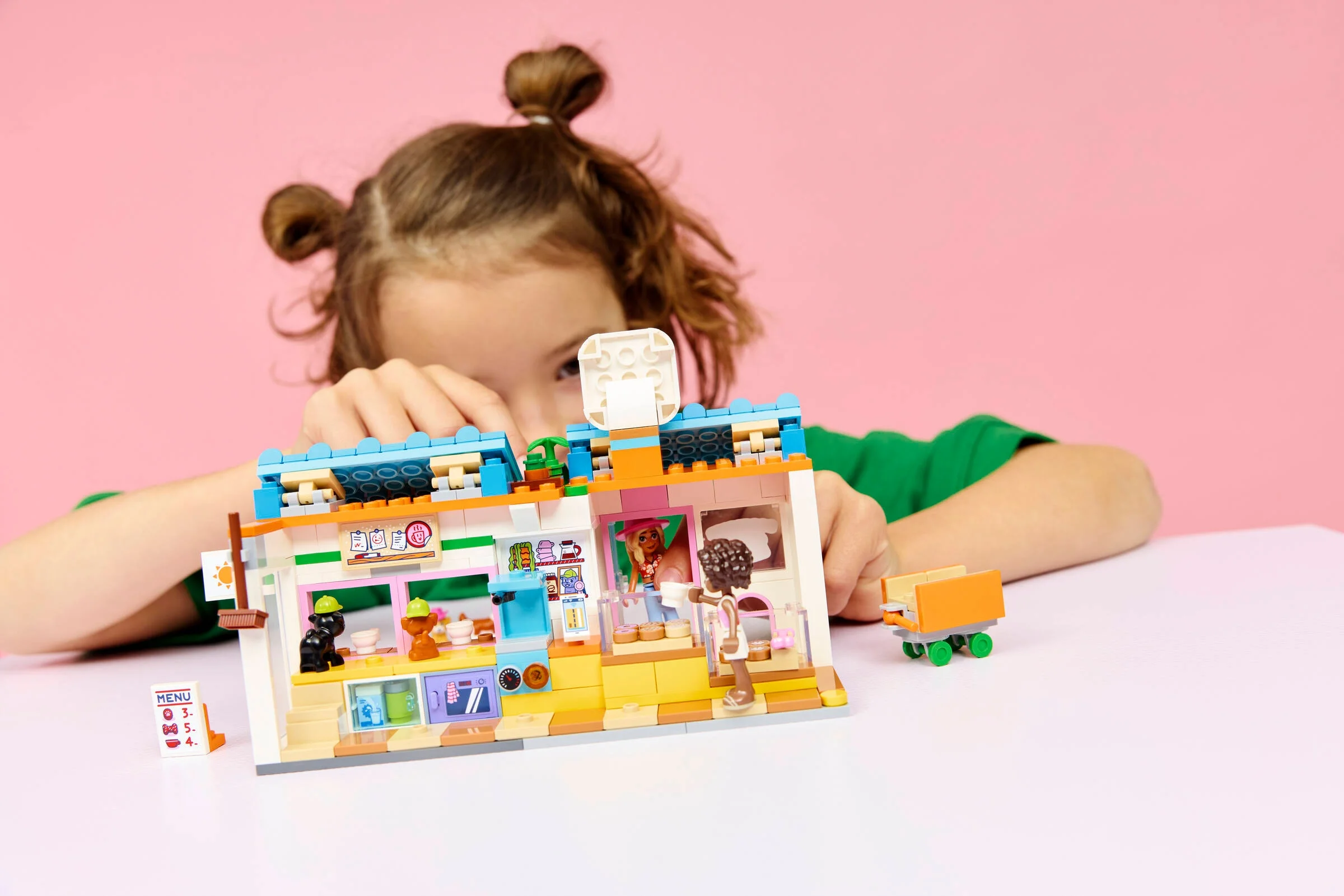 O fată se joacă cu setul LEGO 42677, brutăria pentru câini. Magazinul are detalii drăguțe.