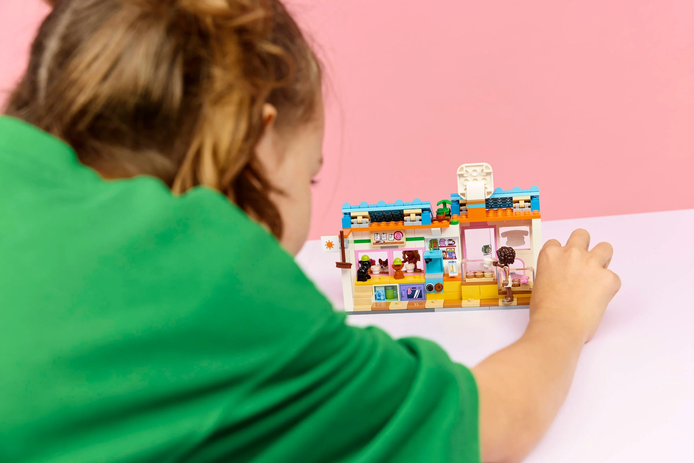 O fată se joacă cu setul LEGO 42677, o brutărie de dulciuri pentru câini.