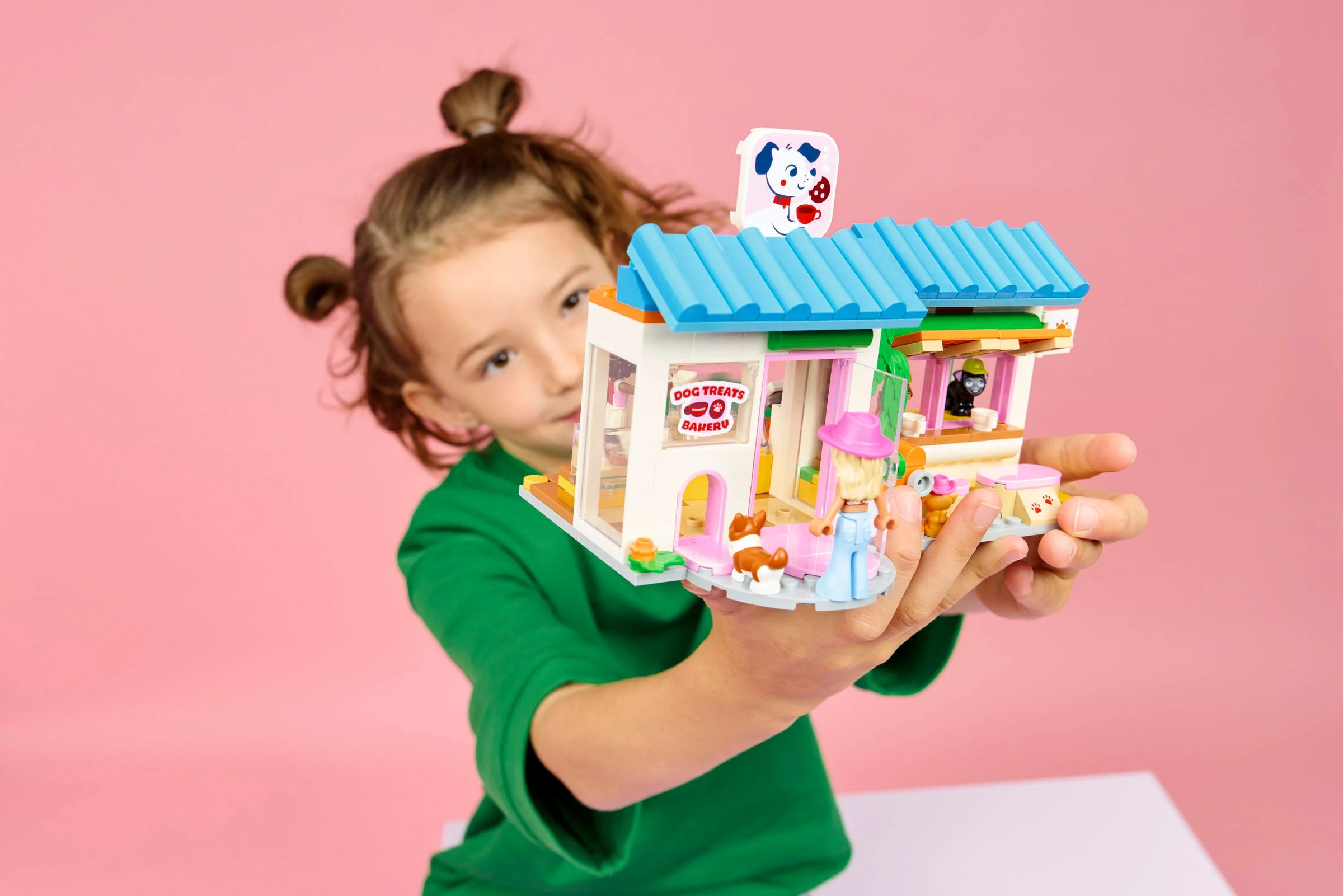 O fetiță prezintă cofetăria pentru câini LEGO Friends. Setul are culori vii și detalii drăguțe.