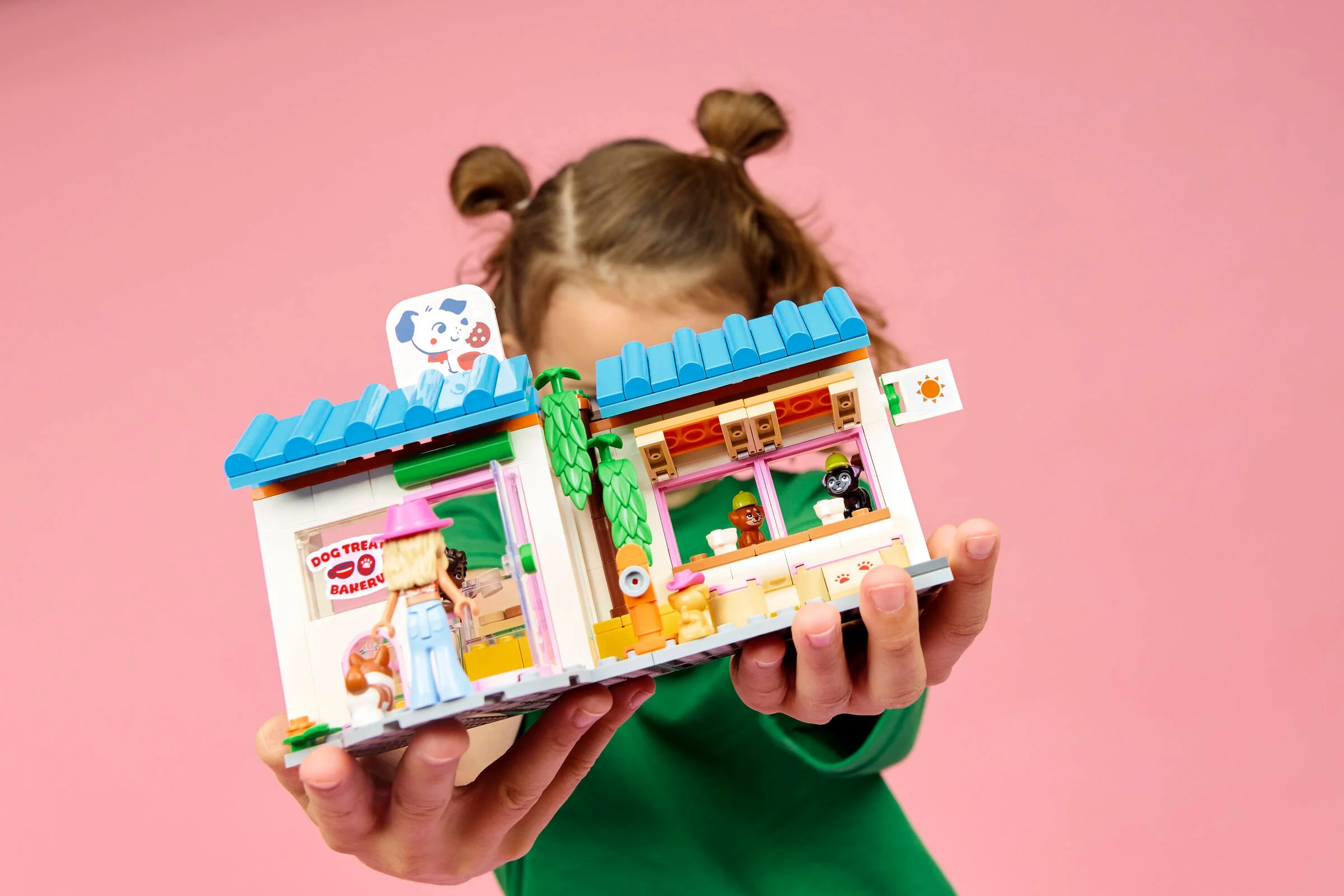 O fetiță ține în mâini brutăria de dulciuri pentru câini LEGO Friends.