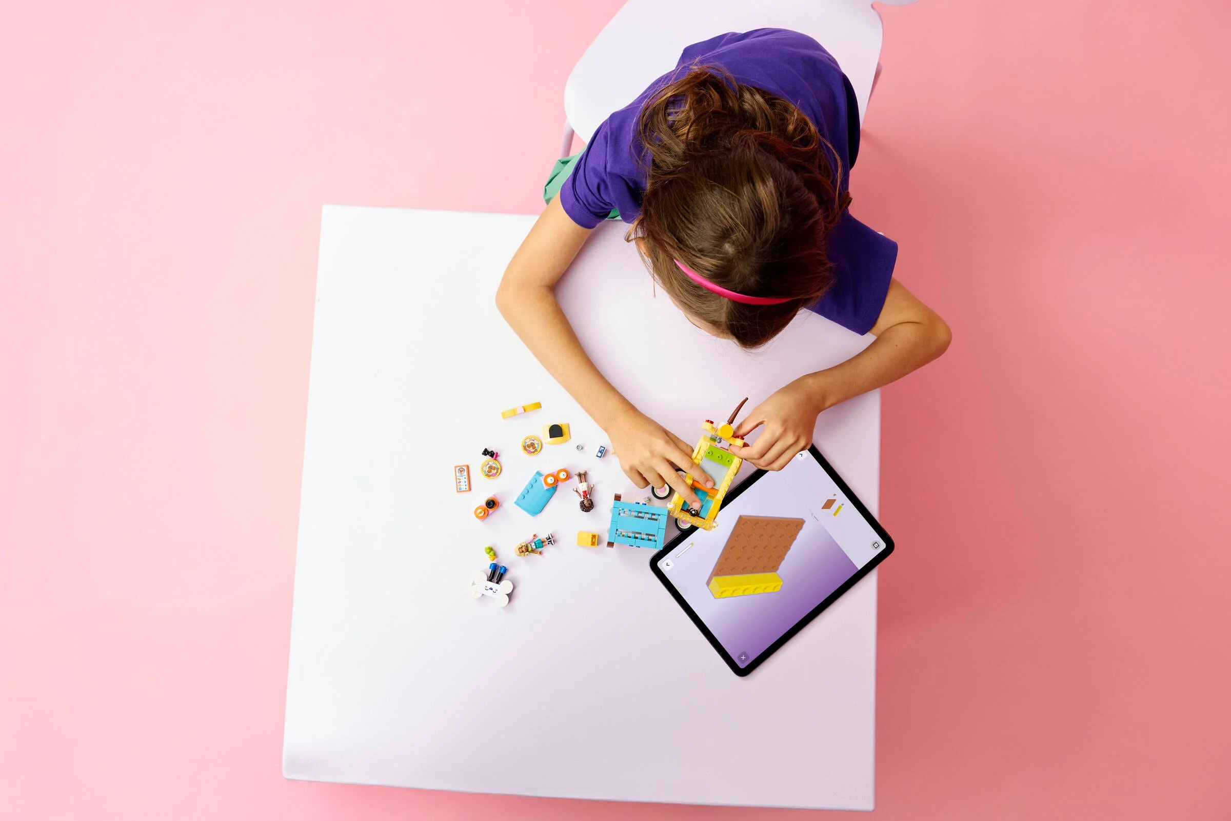 Fetiță construind setul LEGO Friends 42678 cu ajutorul instrucțiunilor digitale pe tabletă.