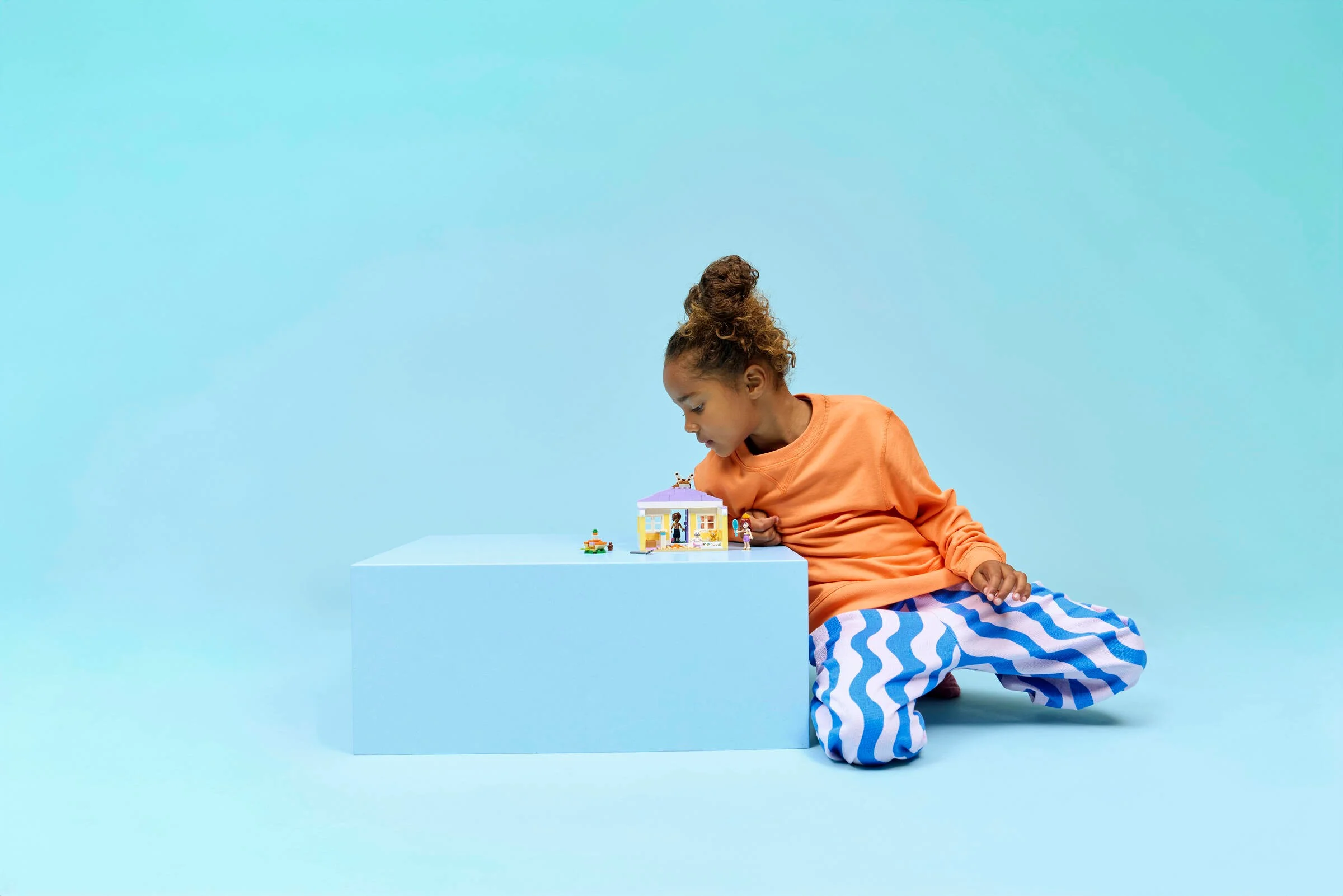 Fetiță se joacă cu hotelul pentru iepurași Heartlake City. Set LEGO Friends 42679.